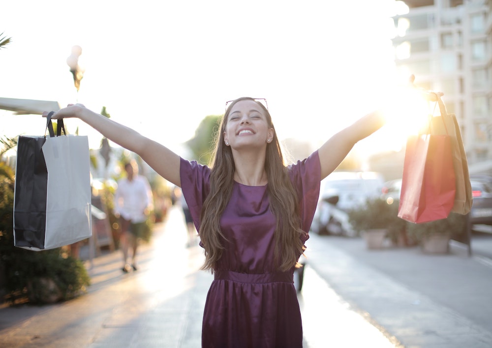 Happy woman shopper holds up shopping bags