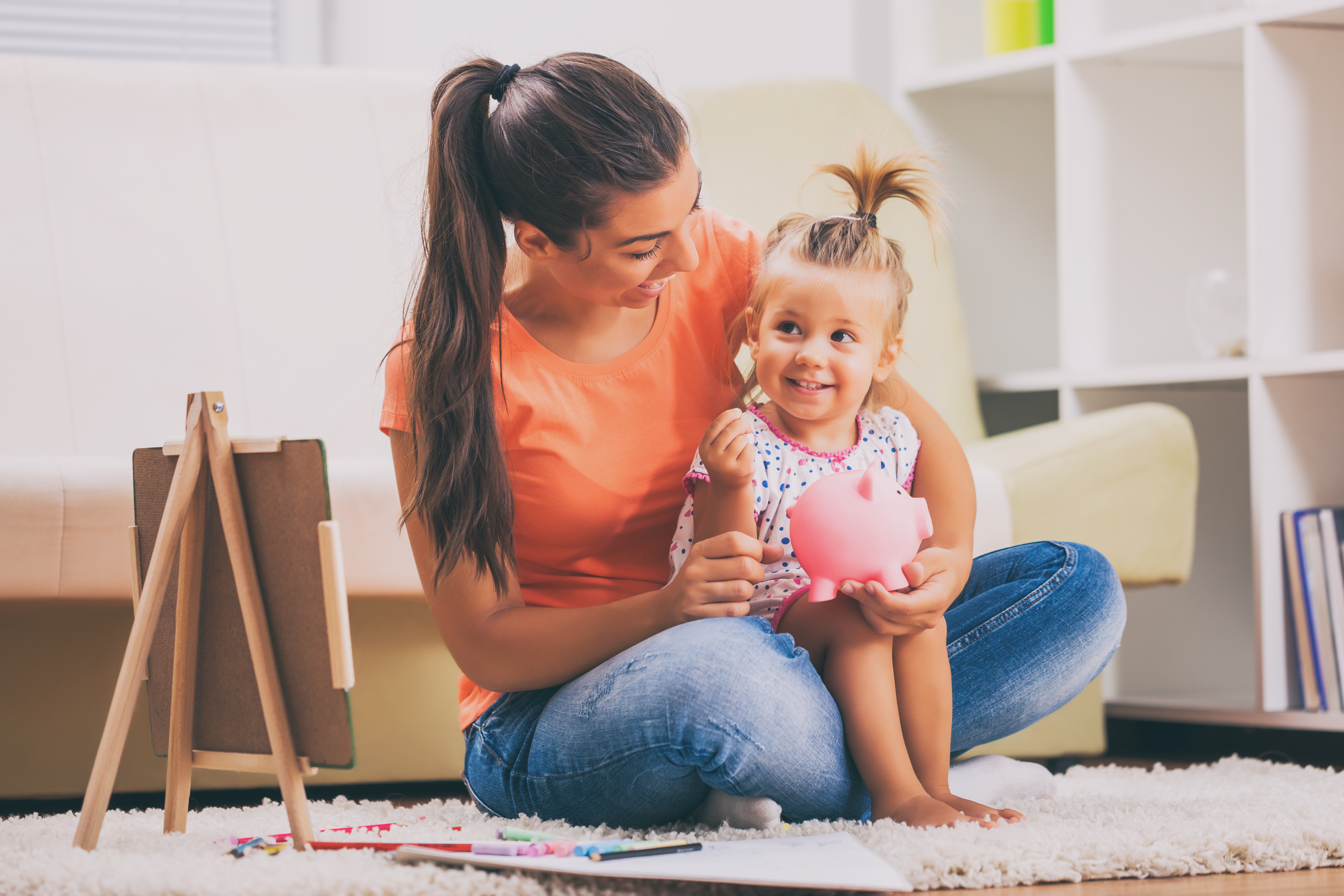 Mother and her child smiling and putting money into a piggy bank