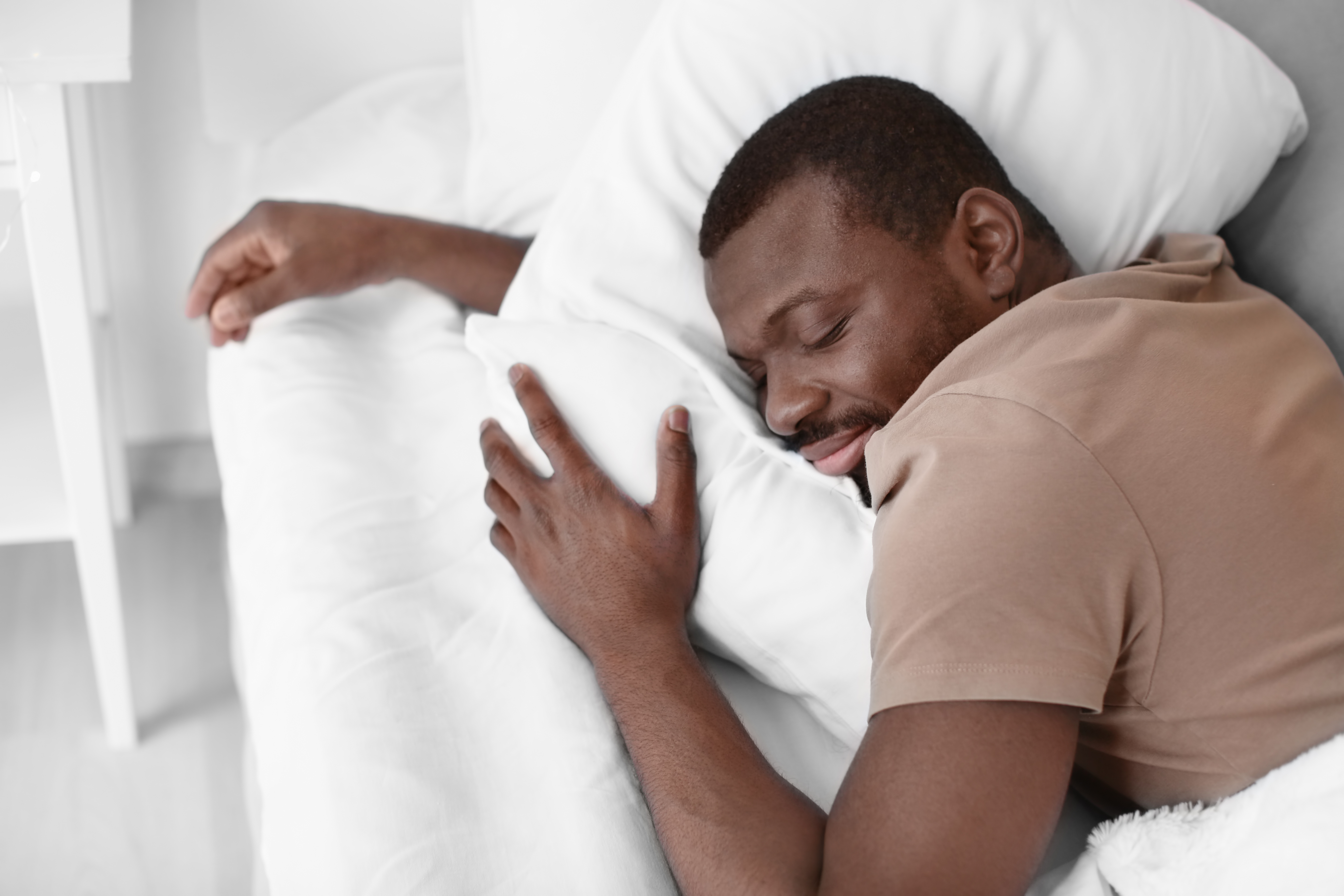 Man wearing a brown t-shirt sleeping in bed