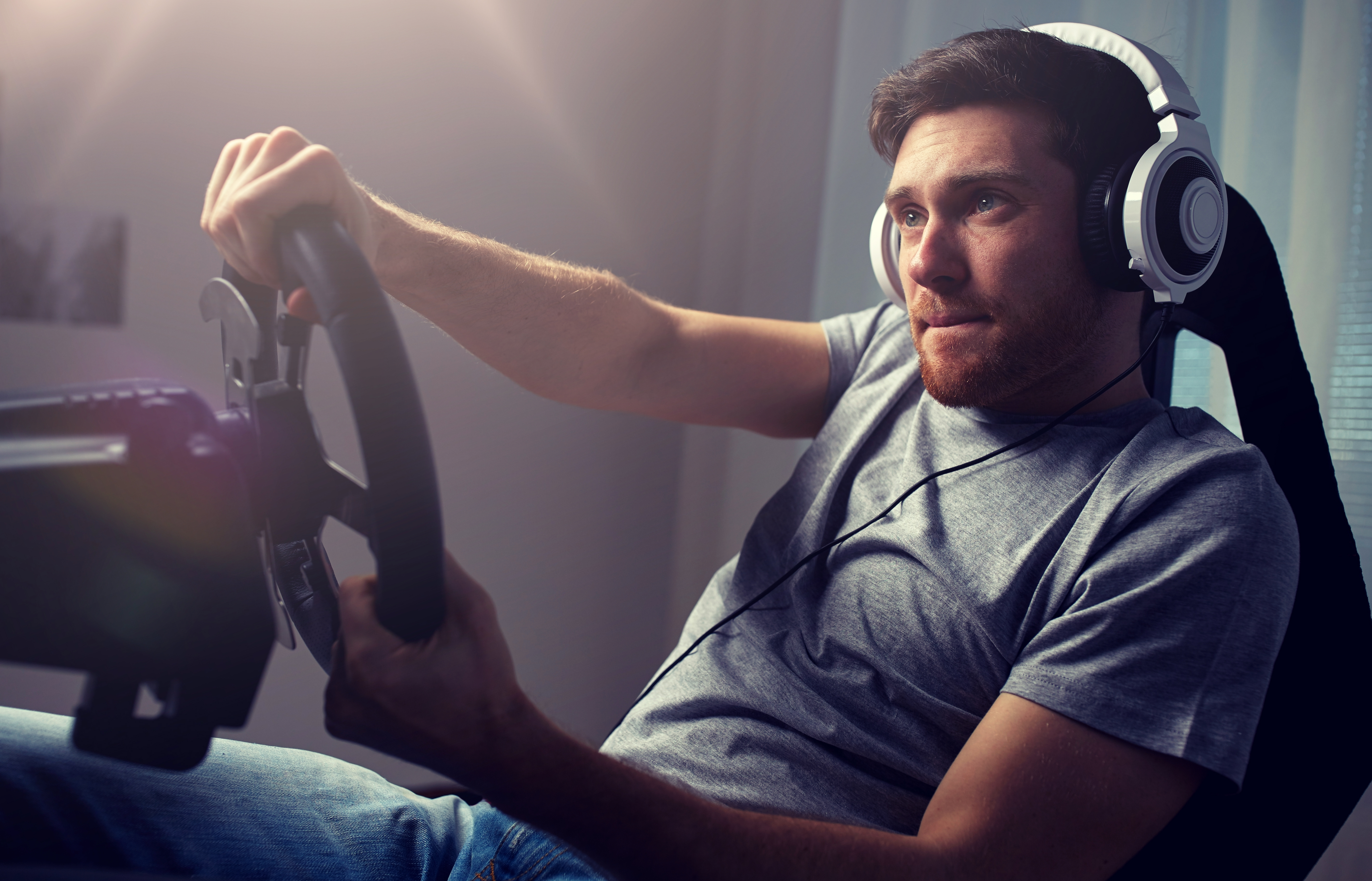 Man using a racing wheel while playing a video game
