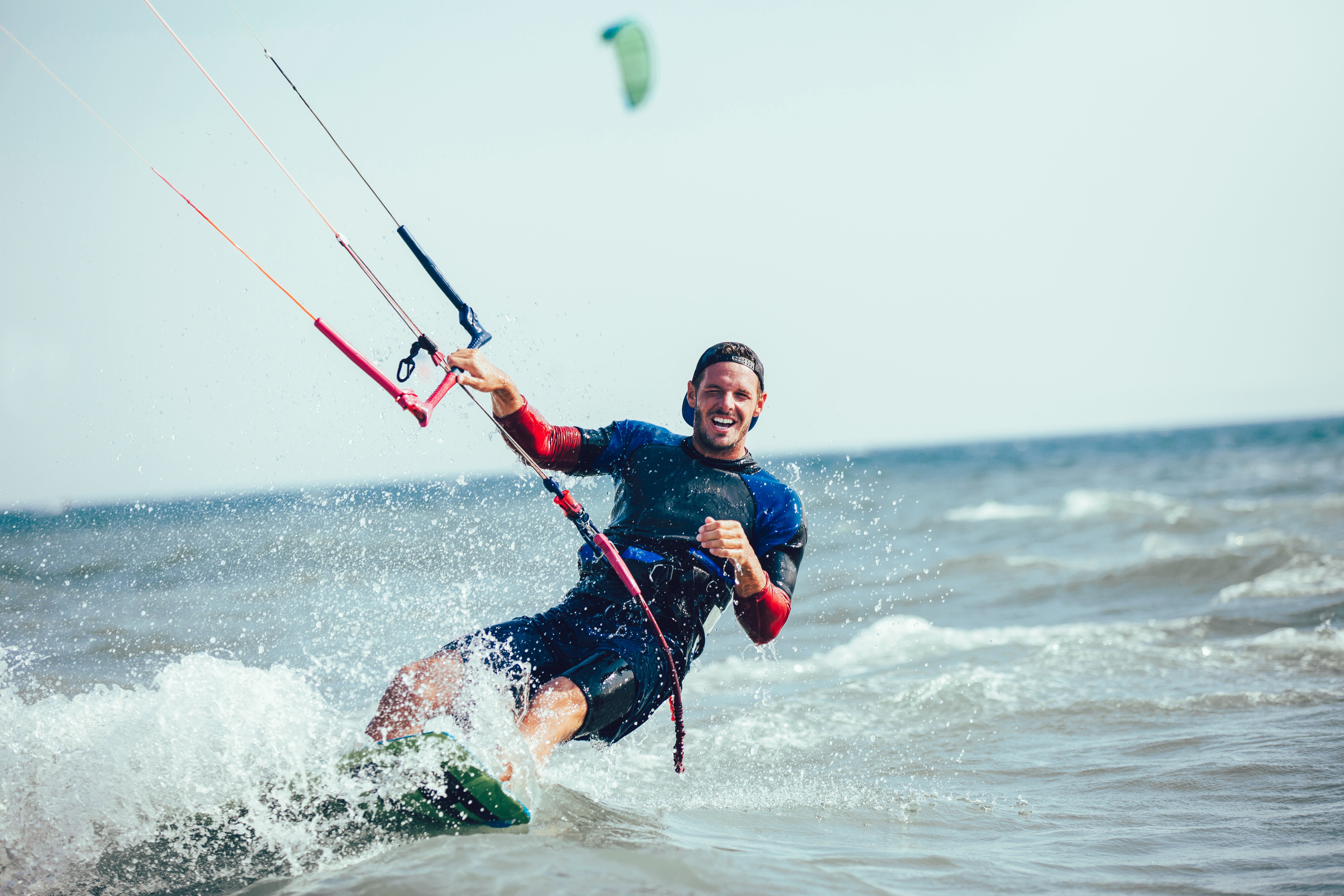 Man wearing a backwards hat and kiteboarding