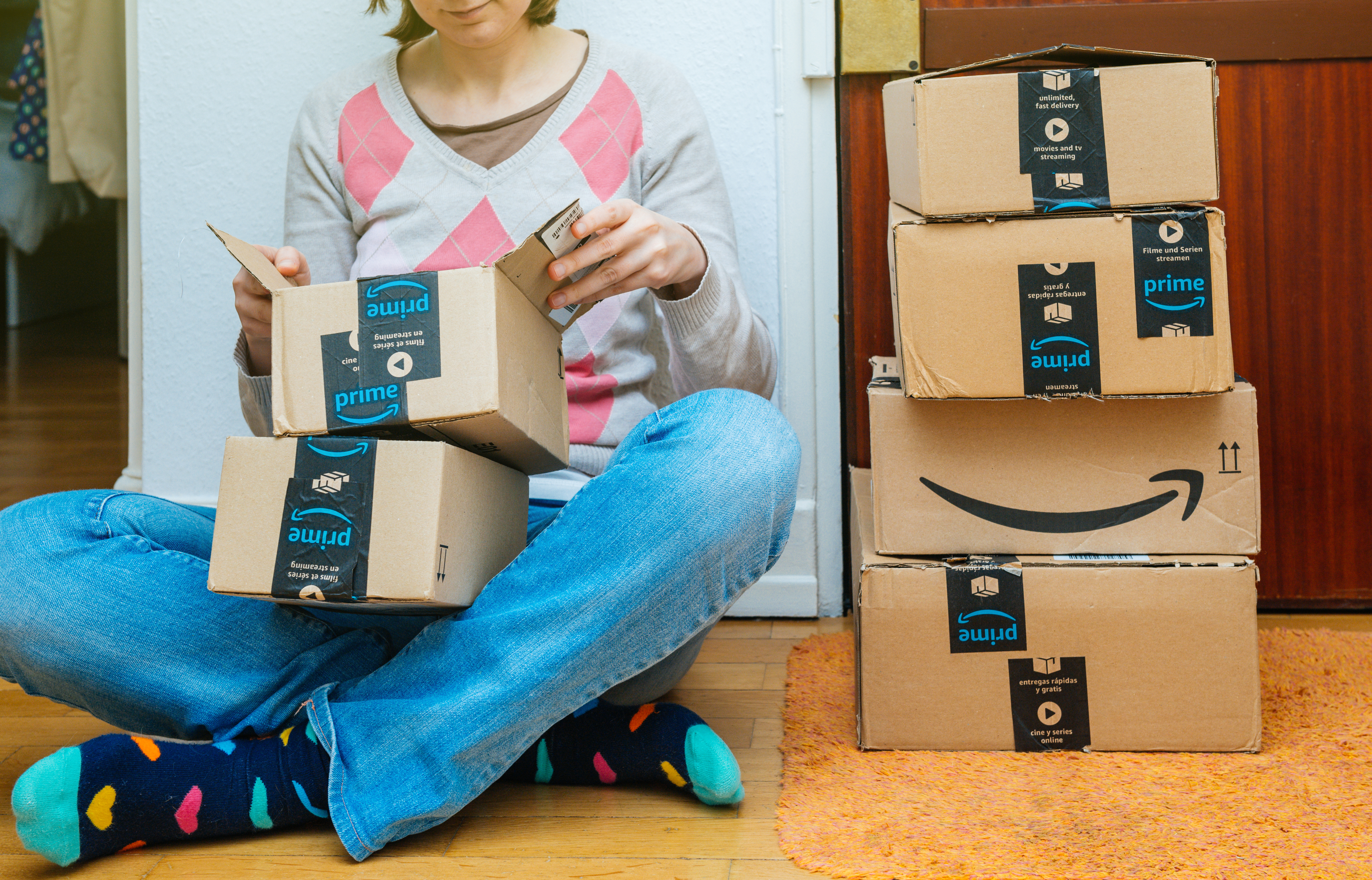 Woman sitting on the ground opening Amazon Prime boxes