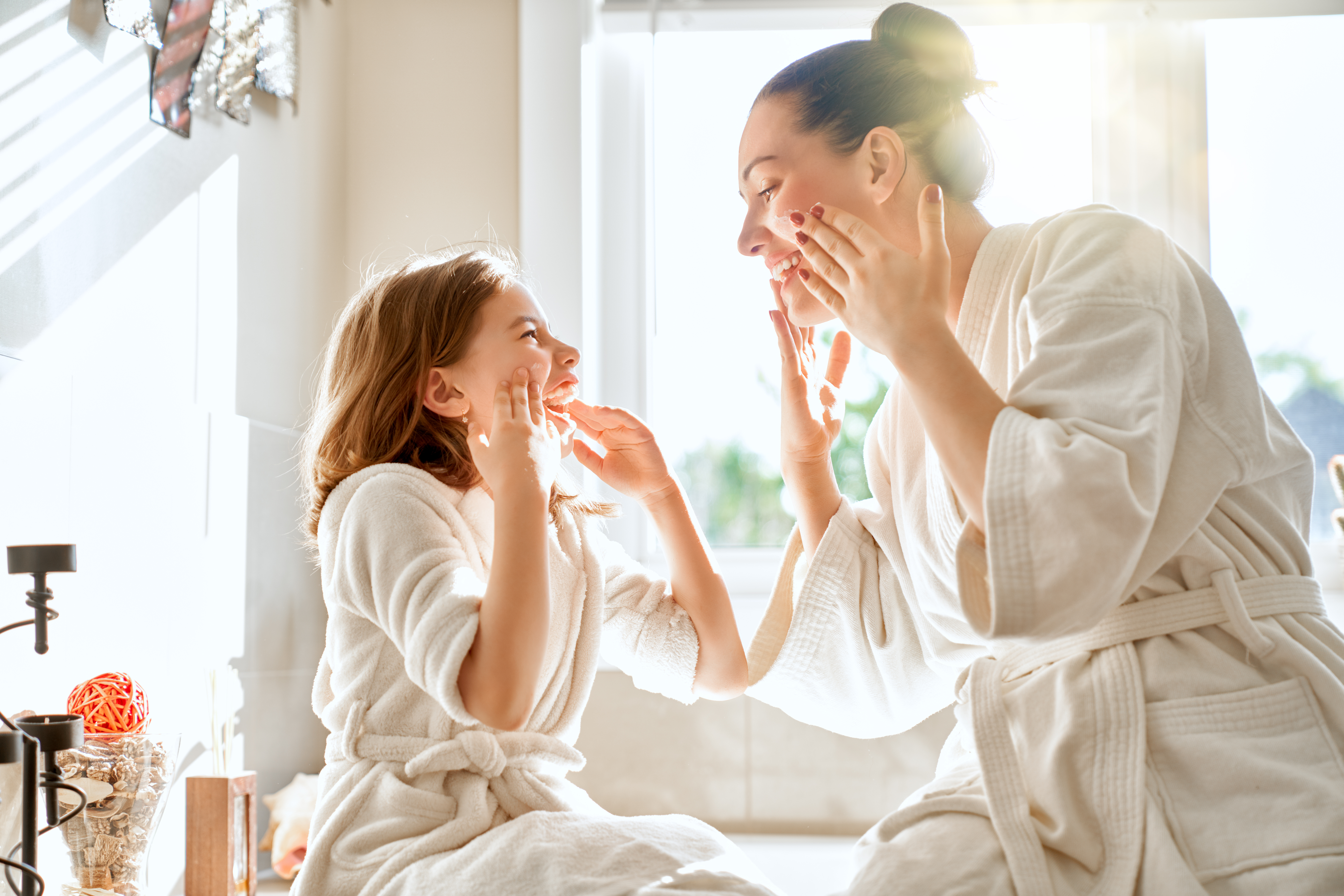 Mother and daughter putting on skincare products