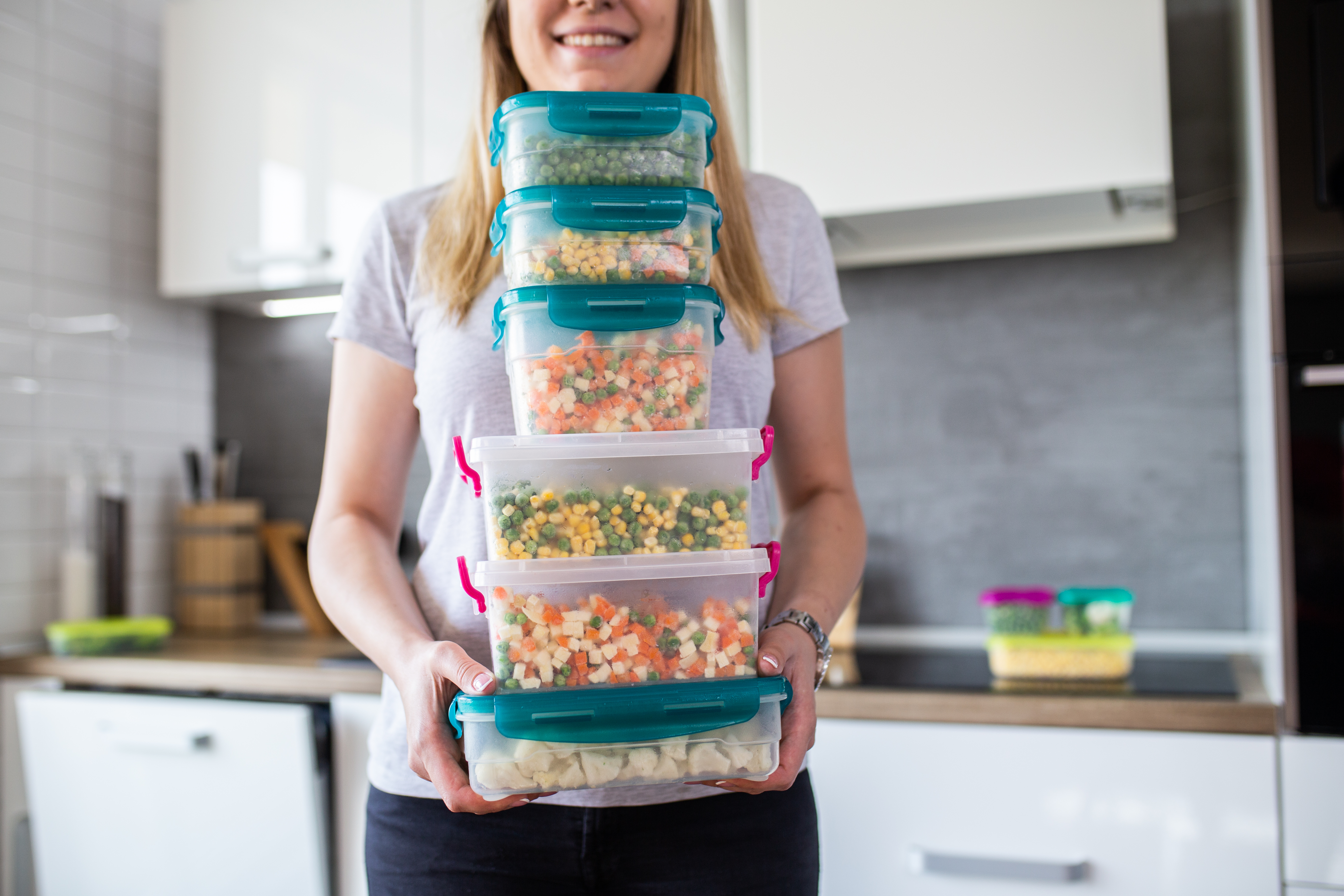 Woman holding a stack of food storage containers