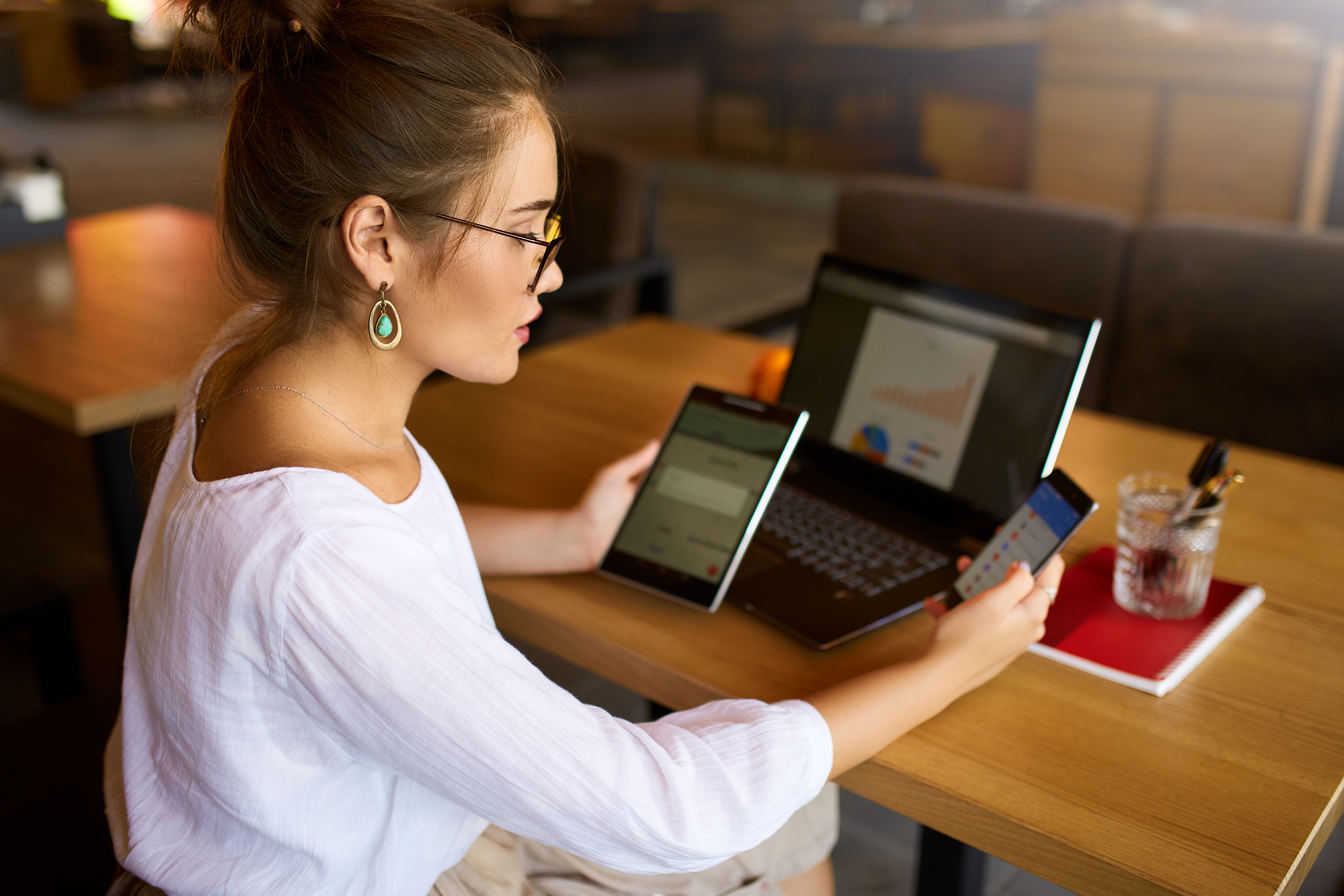 Woman sitting at a table with various electronic devices in front of her