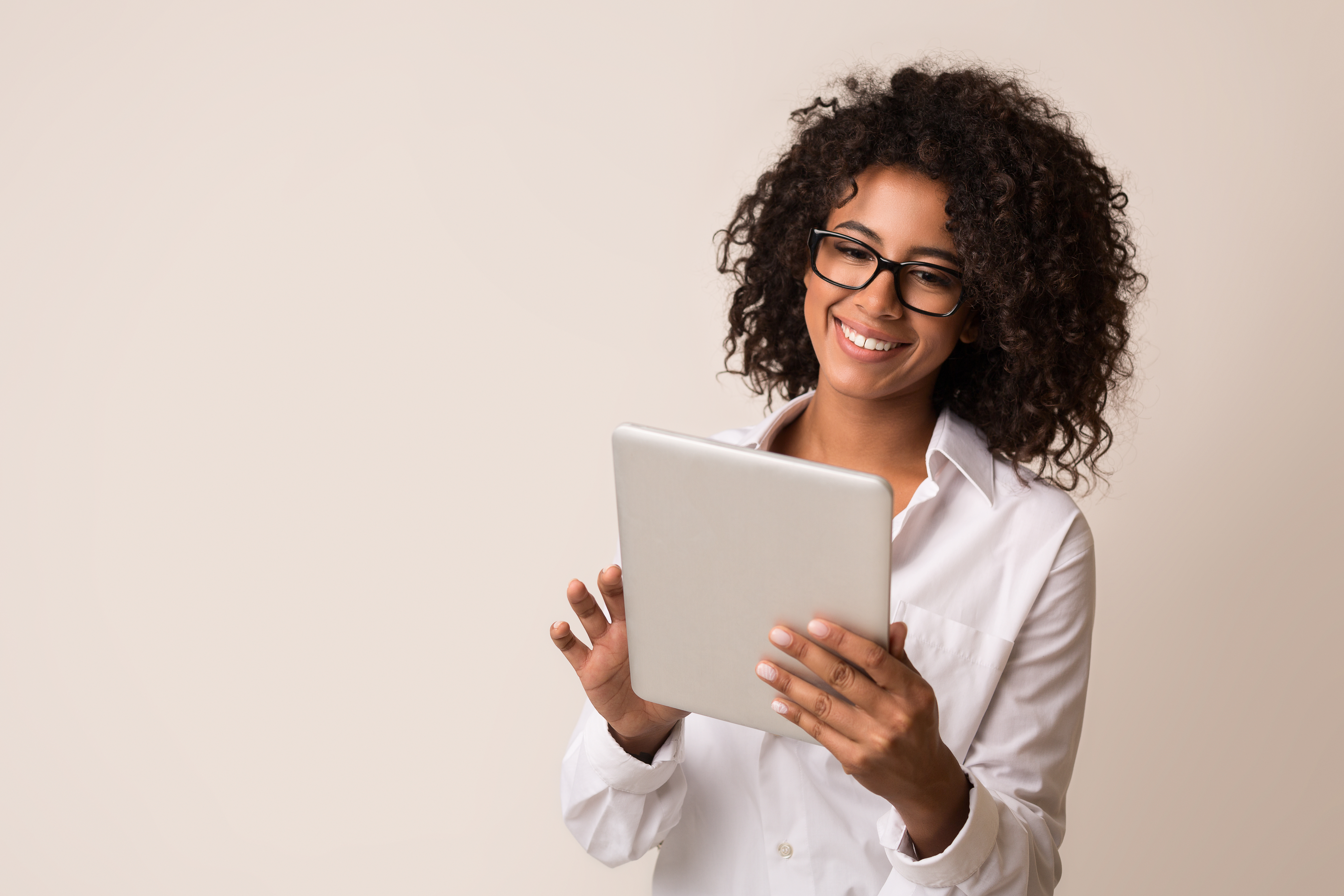 Woman wearing glasses and smiling while using a tablet