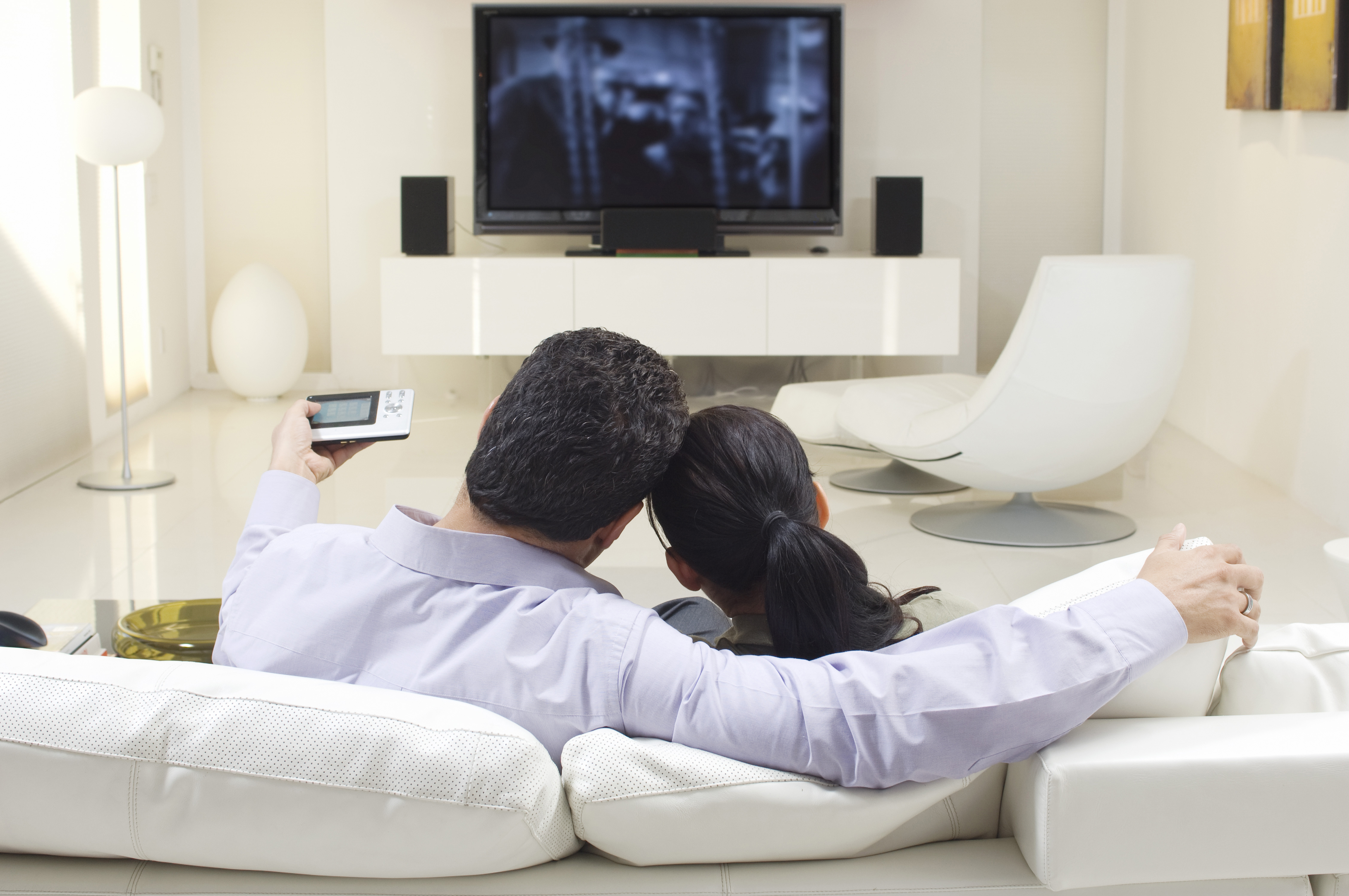 Couple watching tv on white couch