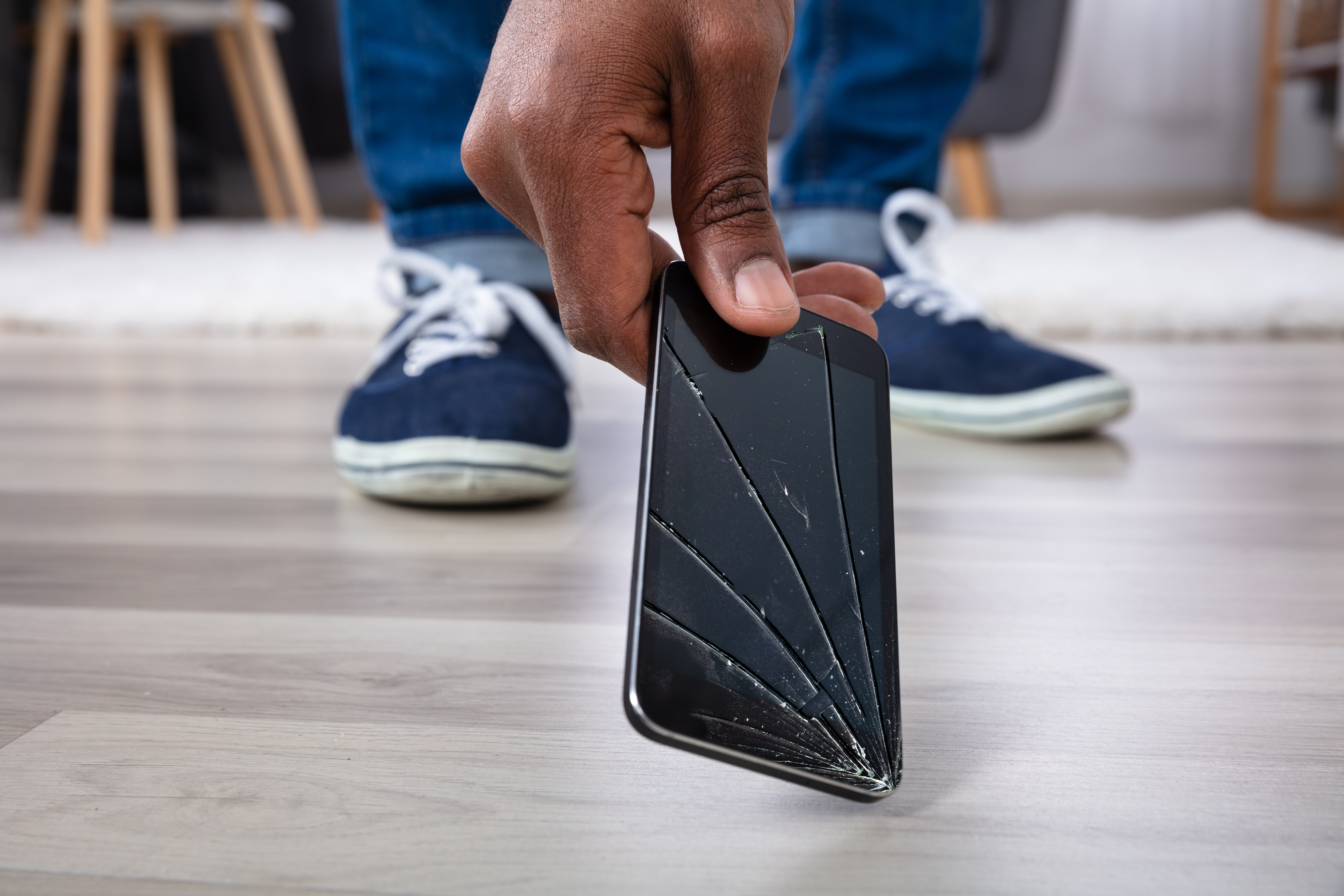Man picking up a cracked smartphone off the ground