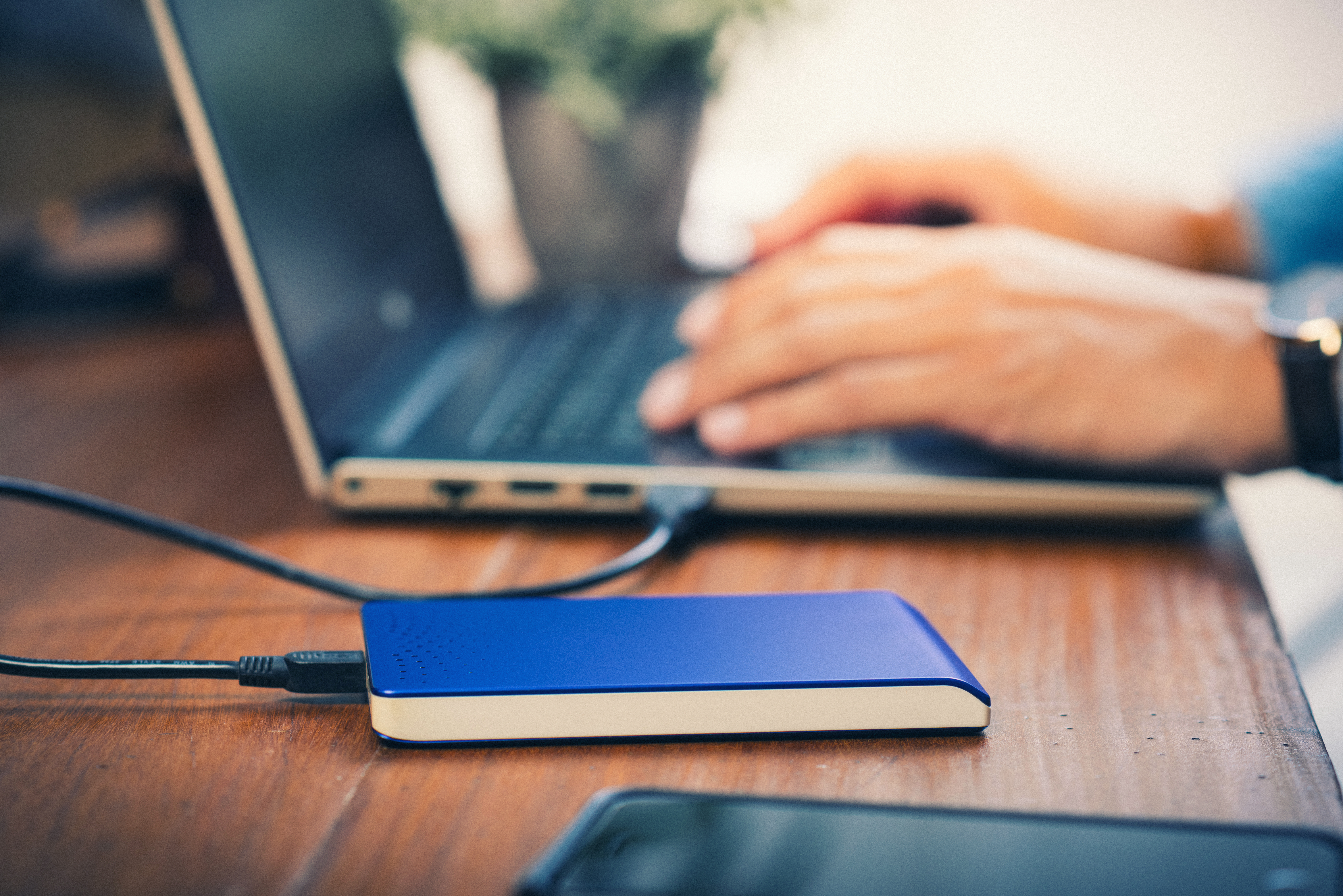 Man typing on his computer backing up data with an external hard drive