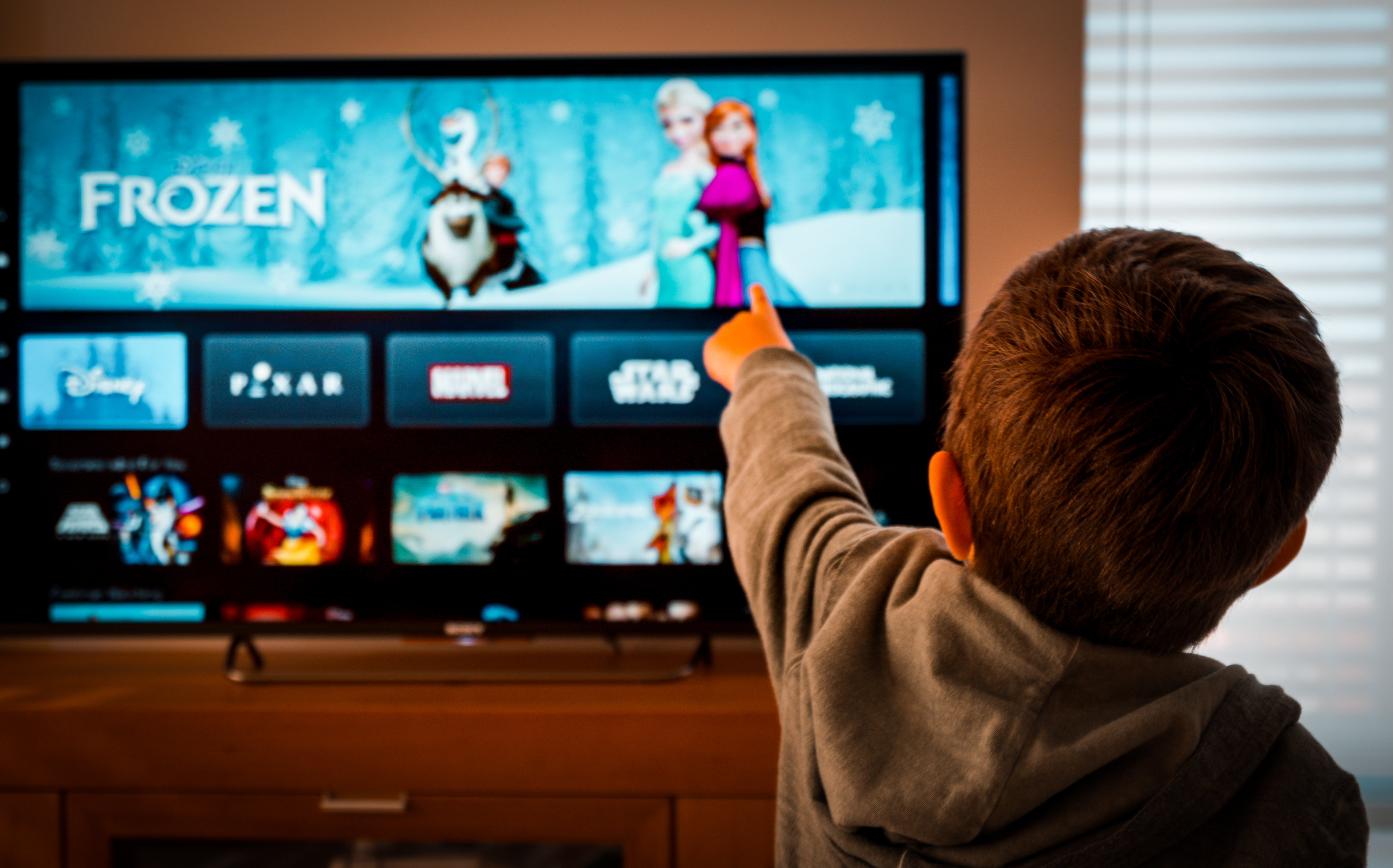 Child pointing at television showing Frozen on Disney+