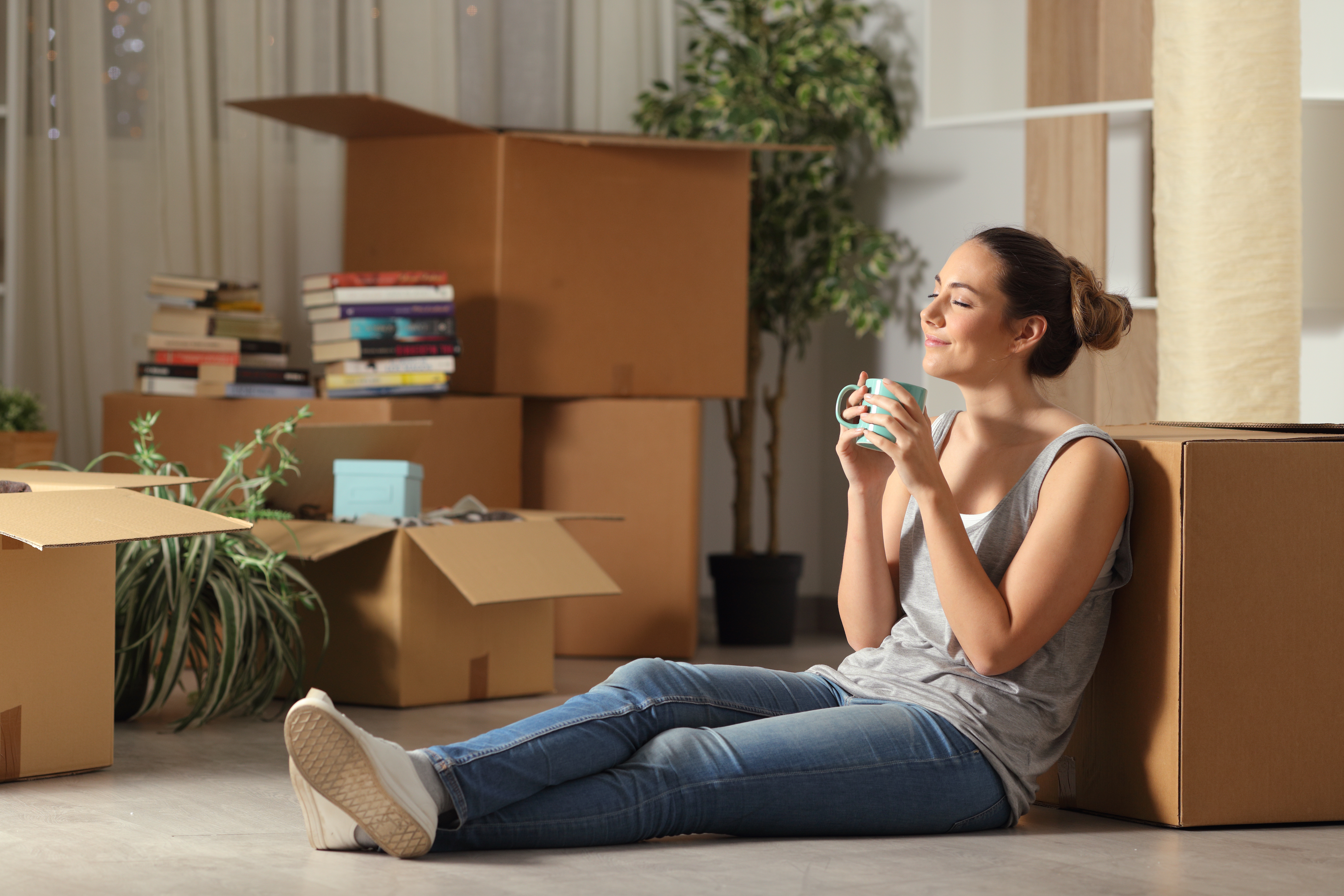 Woman sitting down leaning against cardboard boxes and smiling