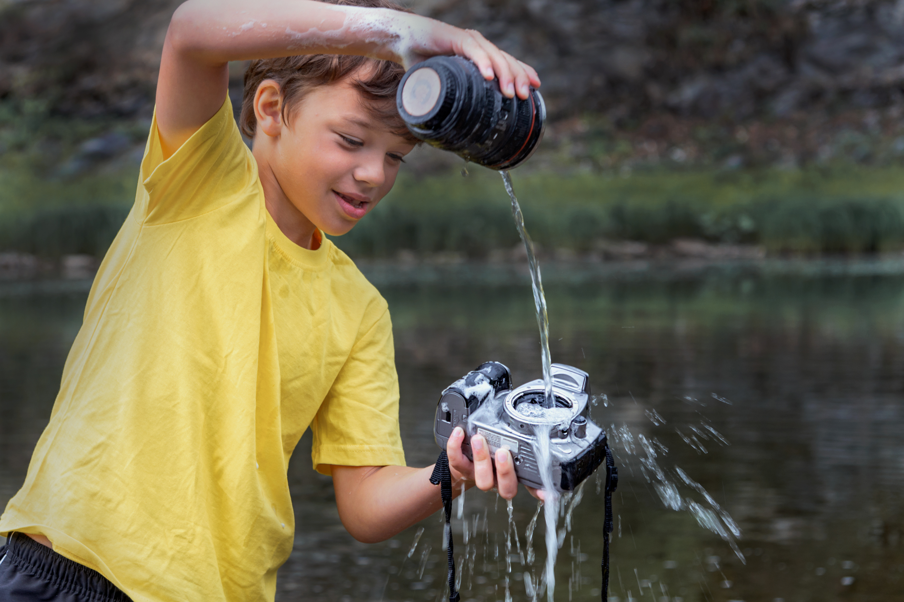 Kid pouring water on a camera