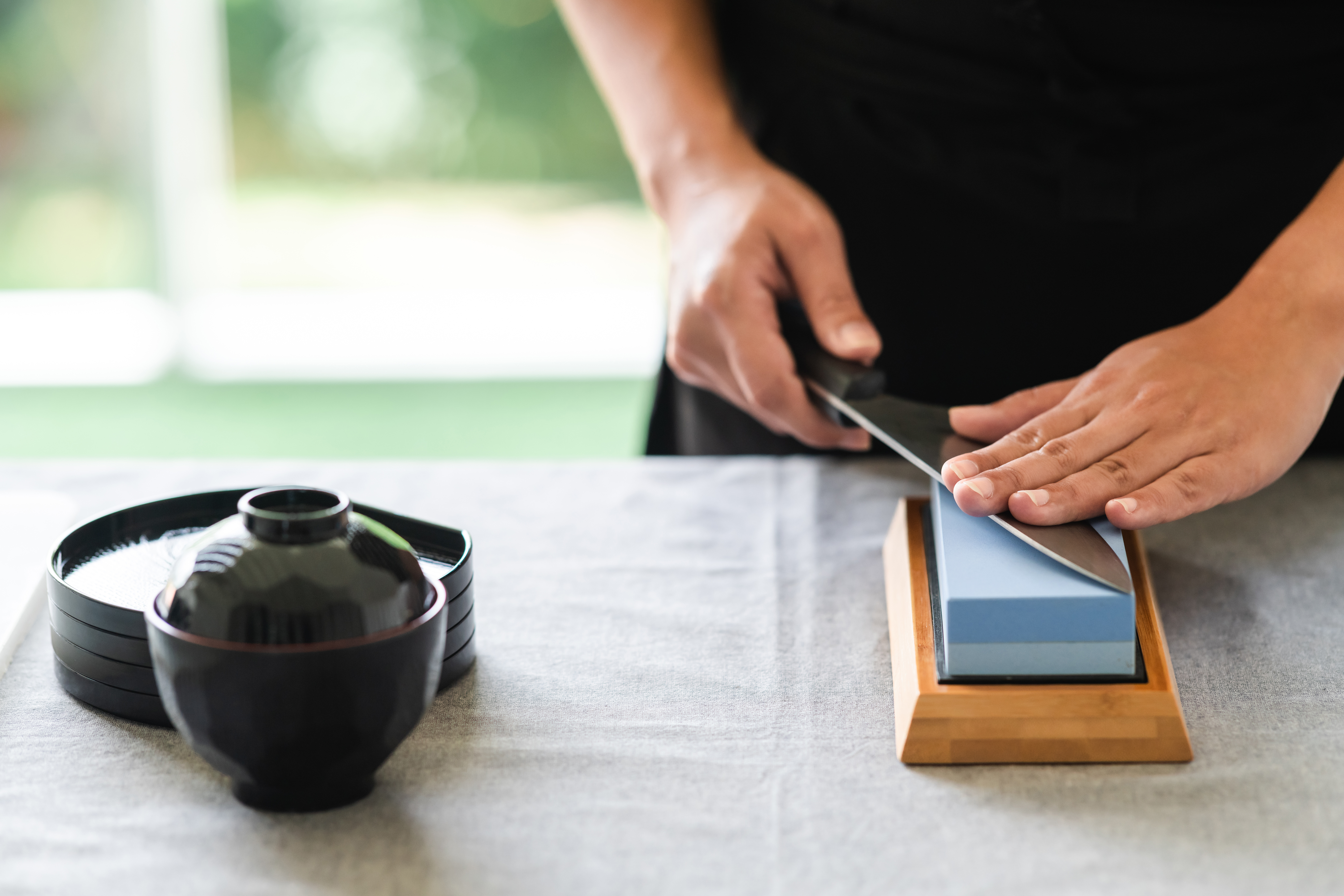 Chef sharpening a kitchen knife on a sharpening stone