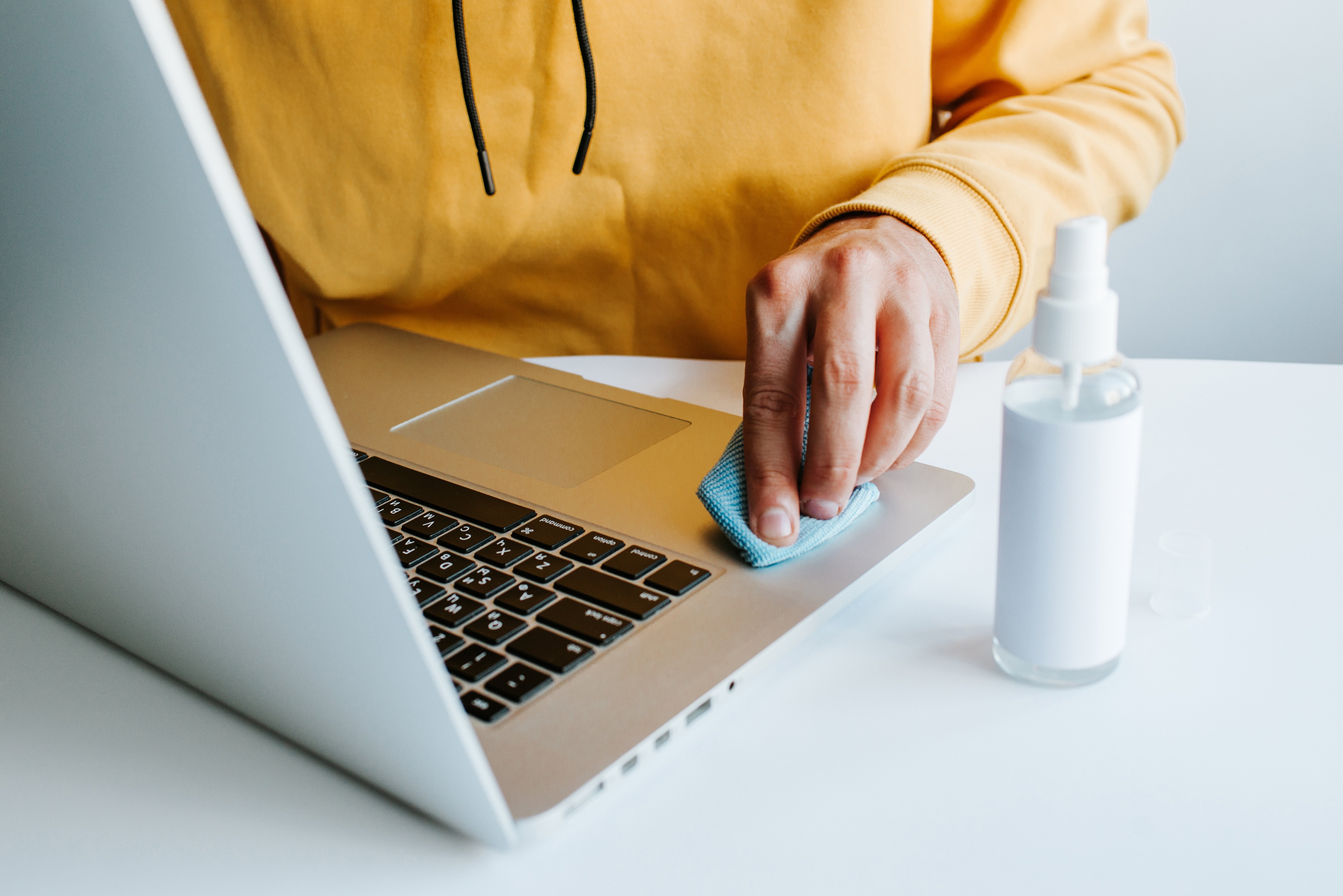 Person using a cloth to clean a MacBook