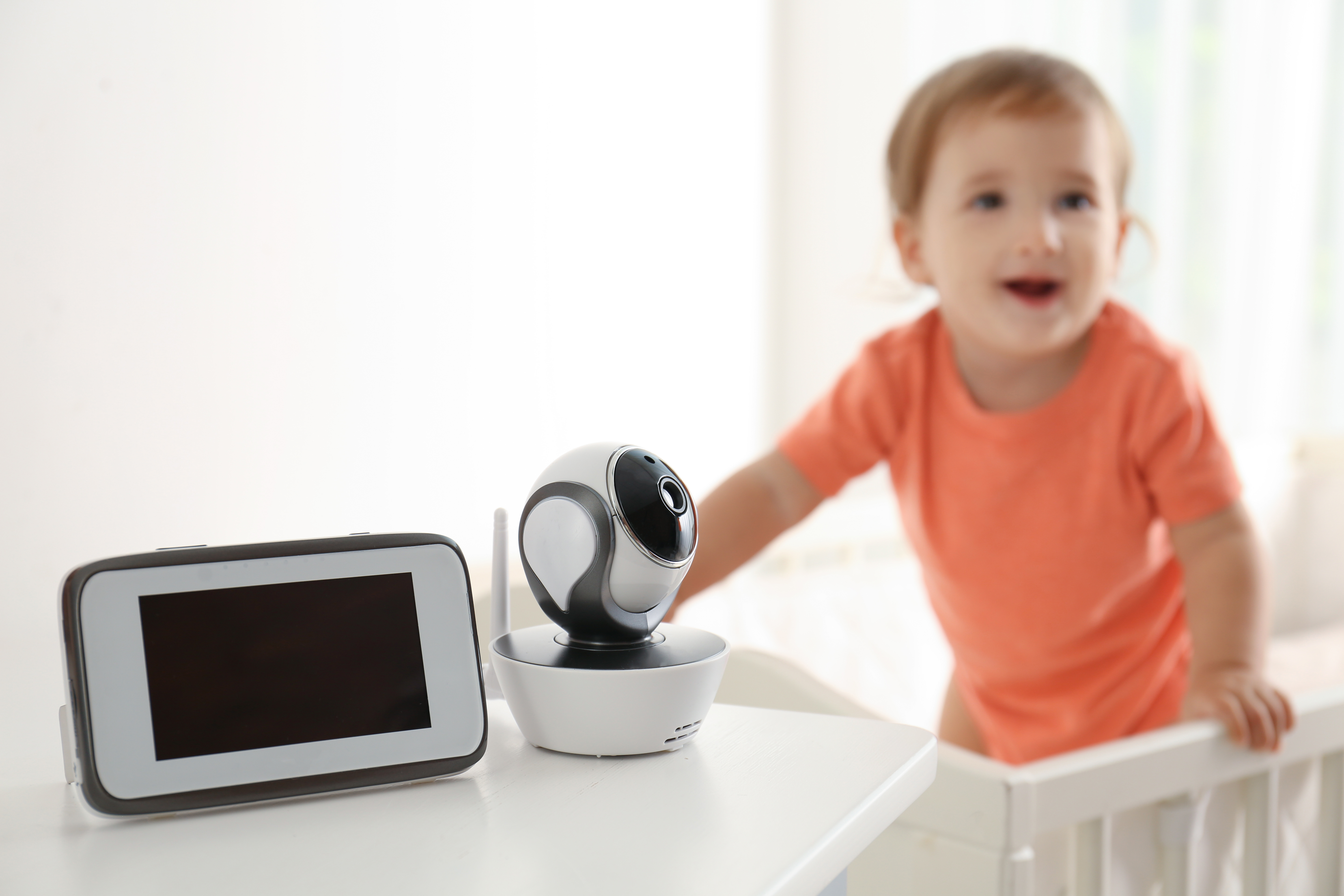 Baby standing in crib next to baby monitor