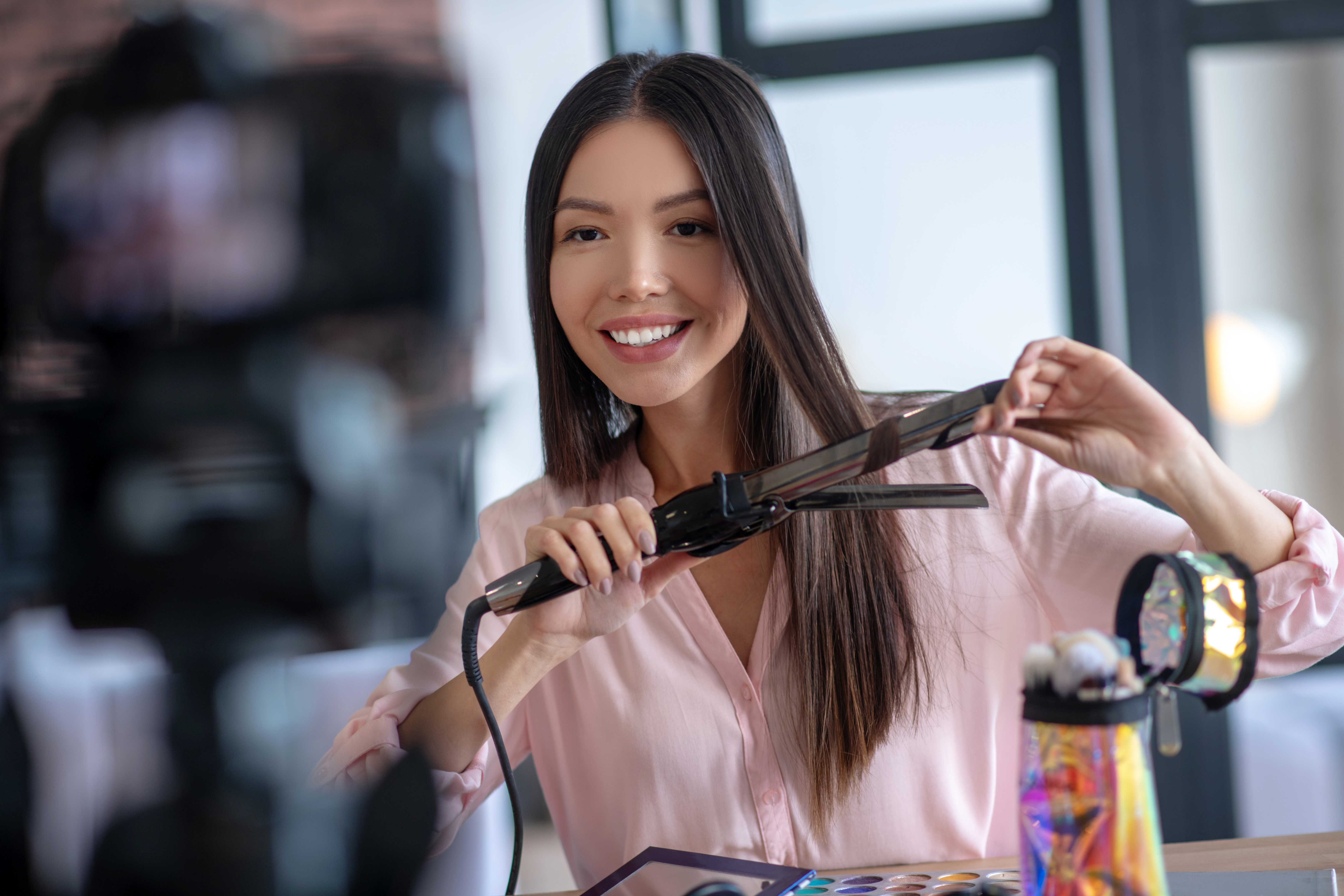 Woman smiling and using a hair styling tool