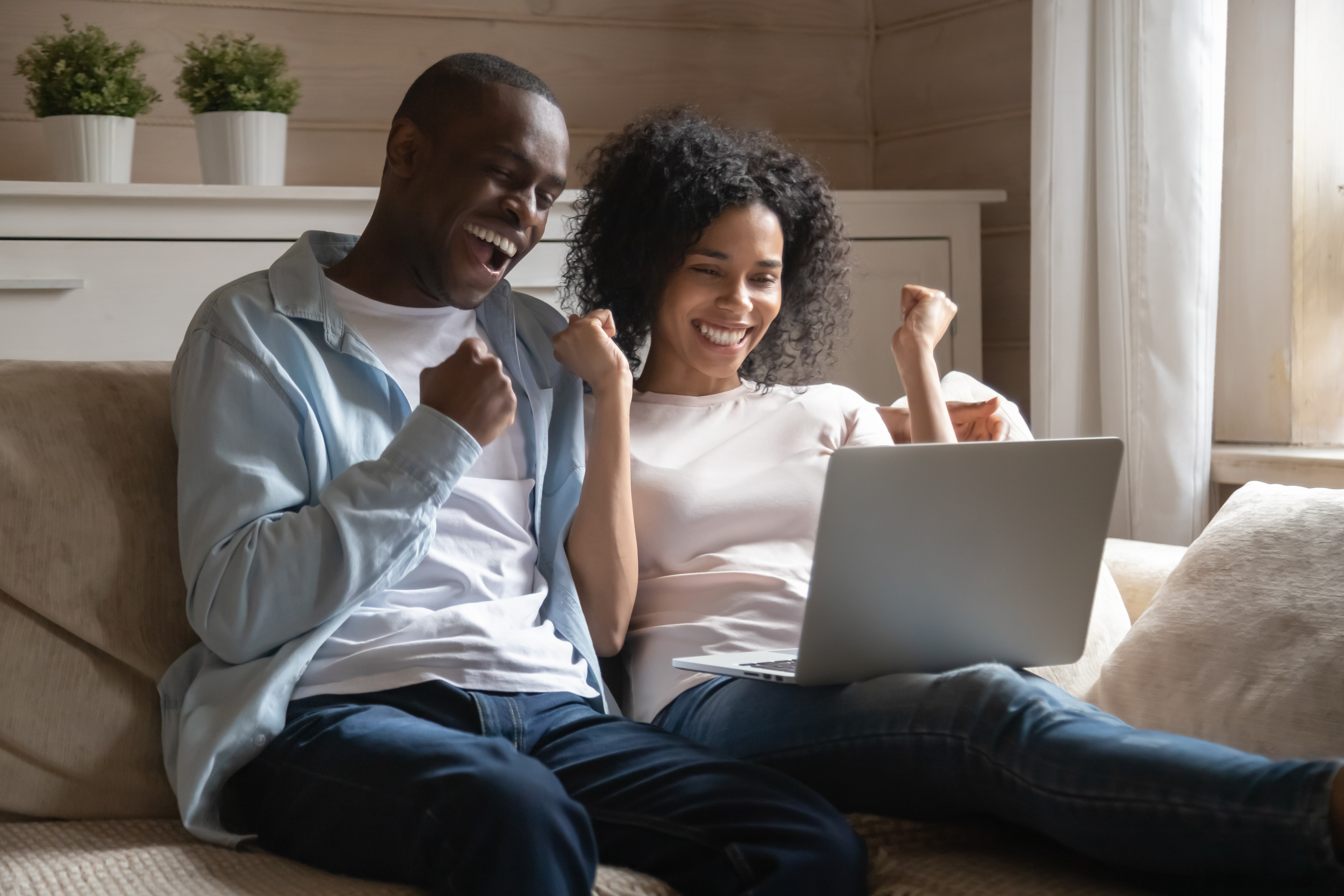Man and woman sitting on couch looking at the computer and smiling