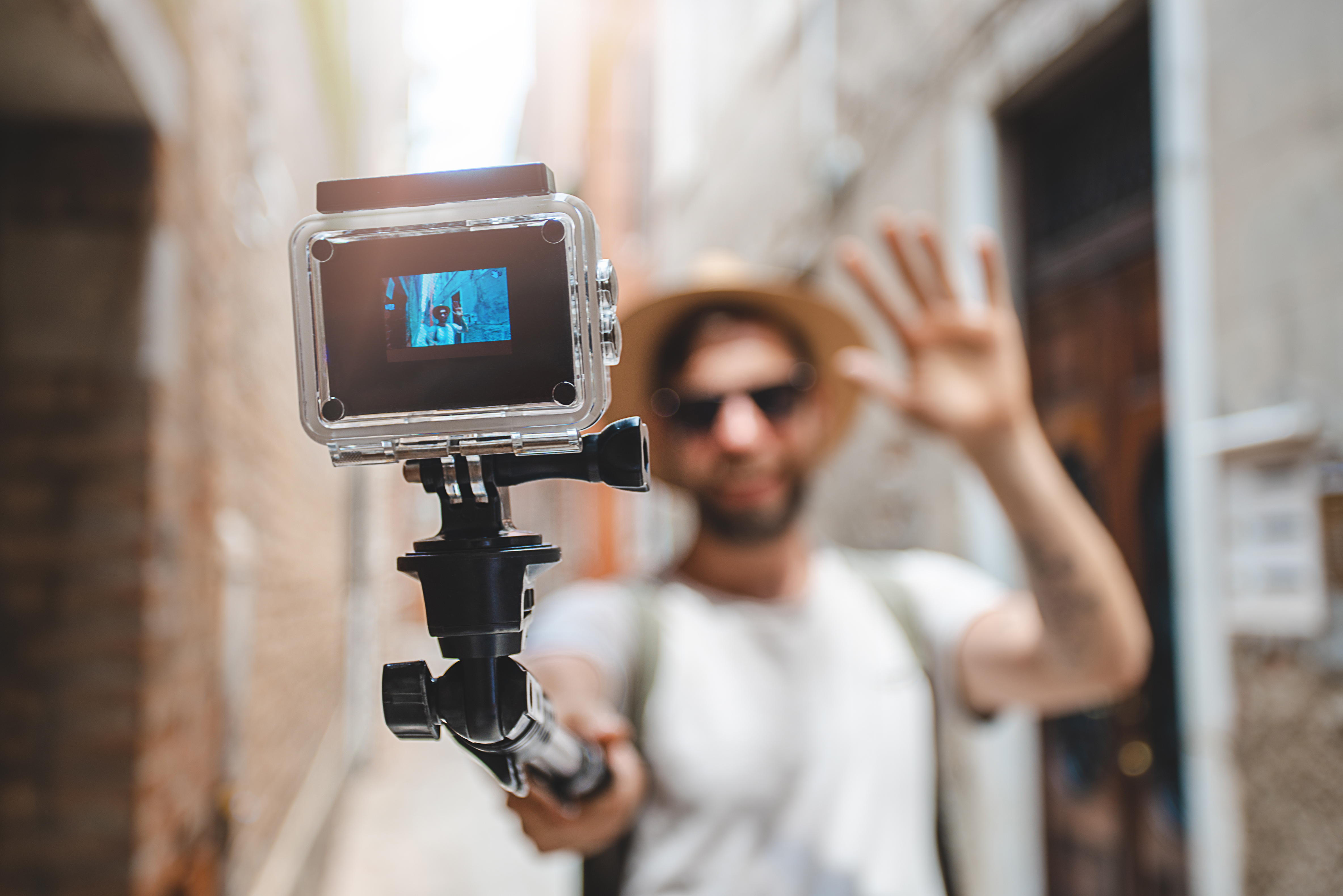 Man with an action camera attached to a selfie stick waving