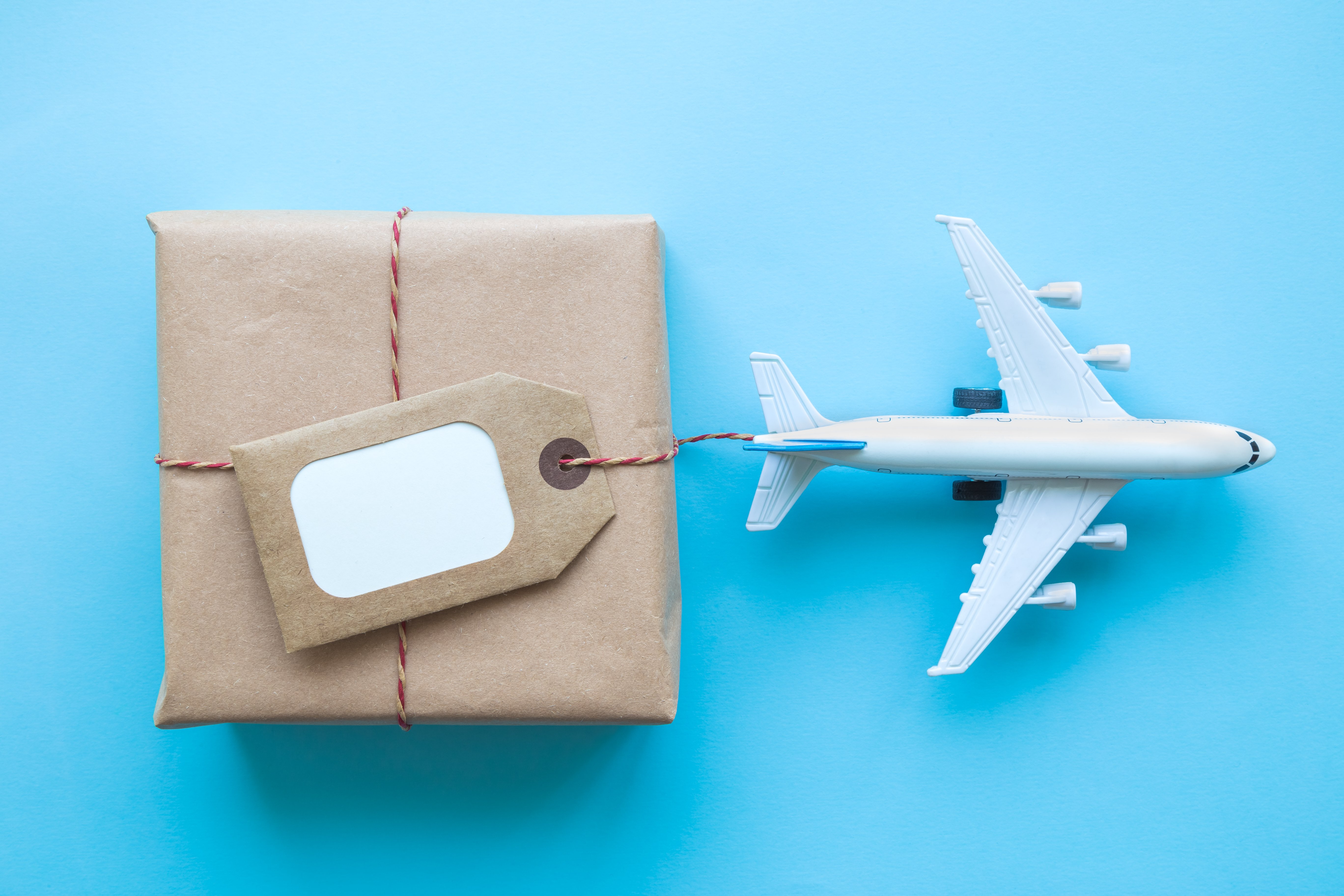 Toy plane attached by a string to a package wrapped in brown paper