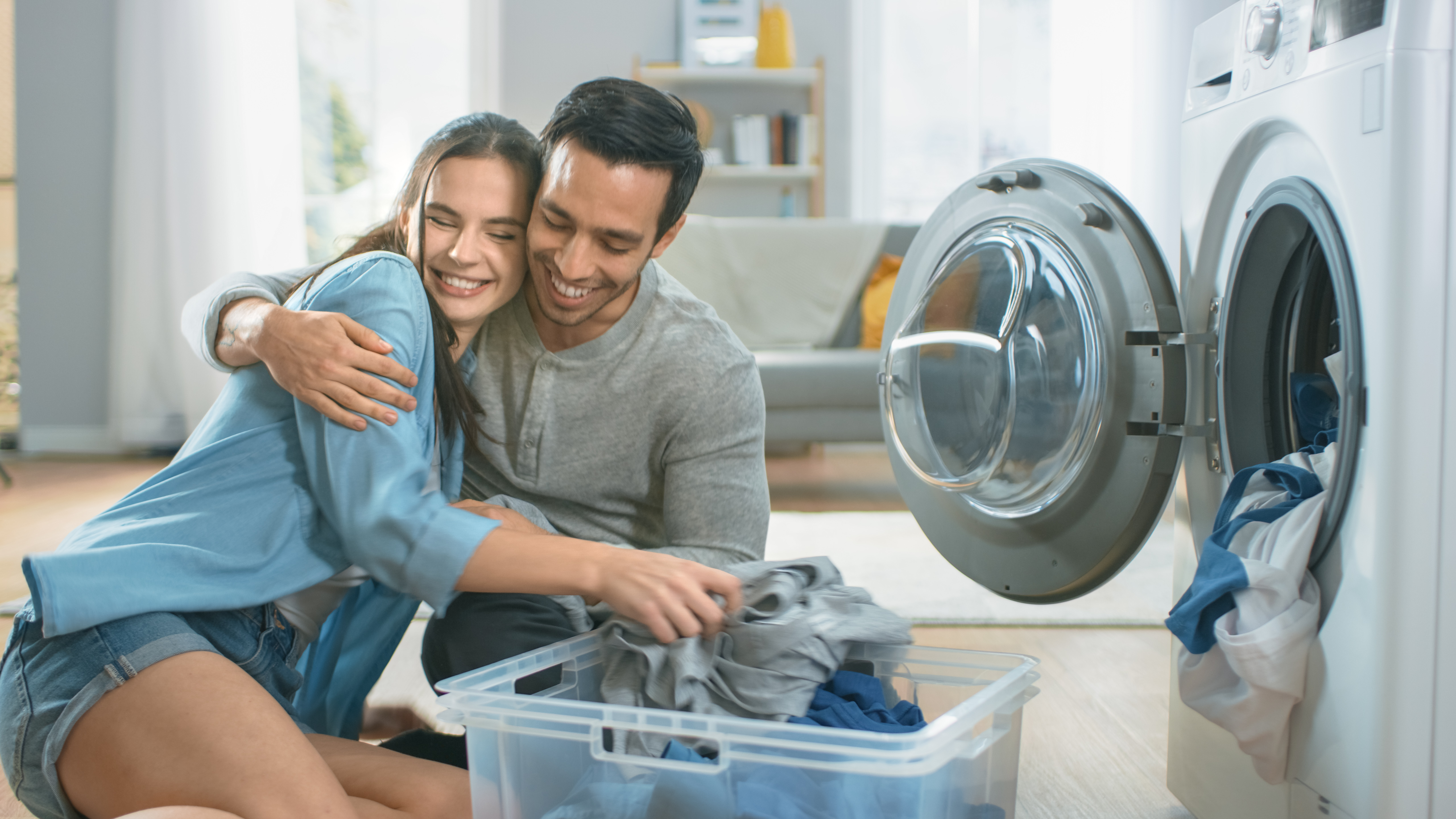 Man and woman hugging while doing laundry