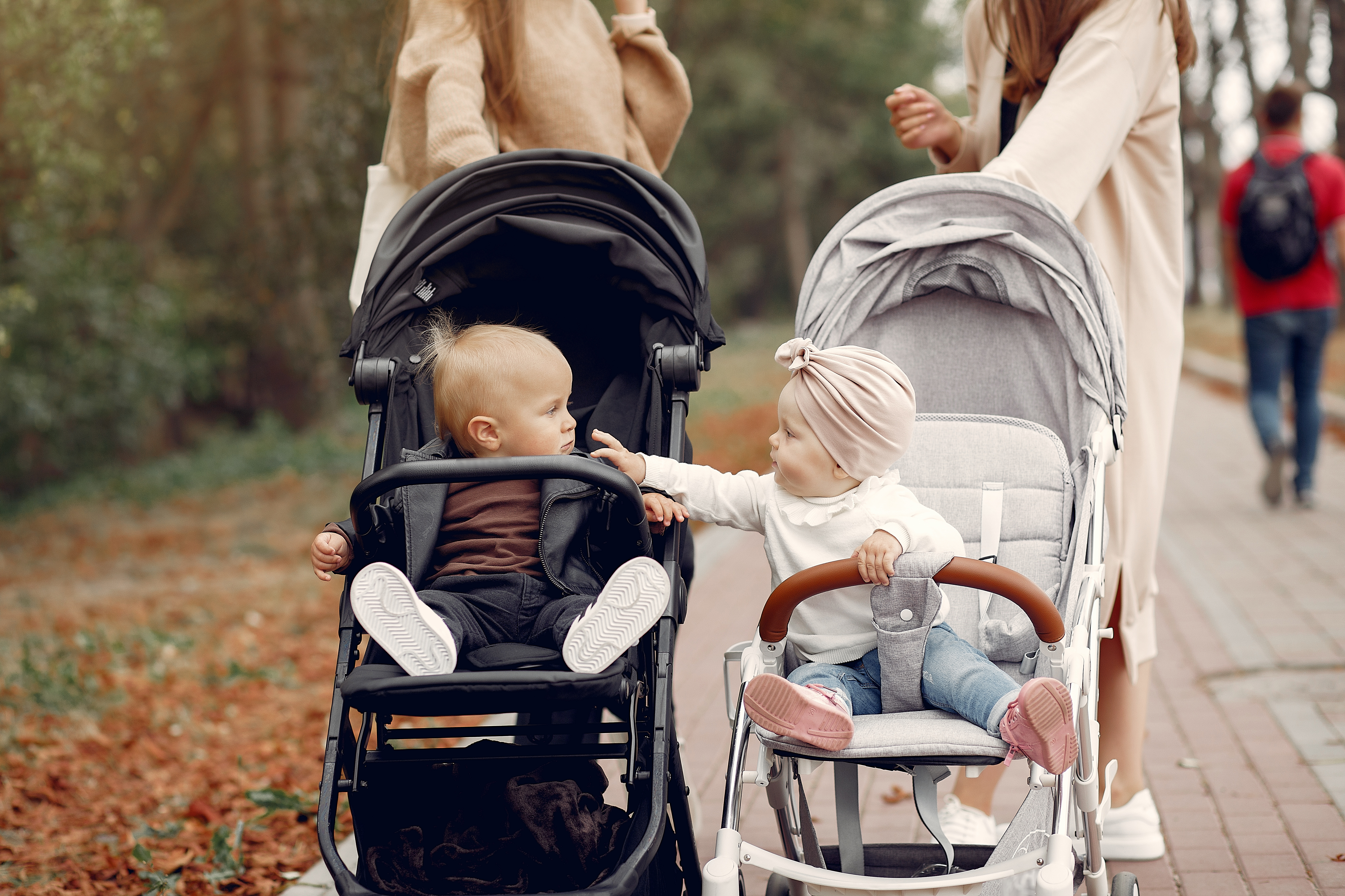 Two babies playing with each other in separate strollers