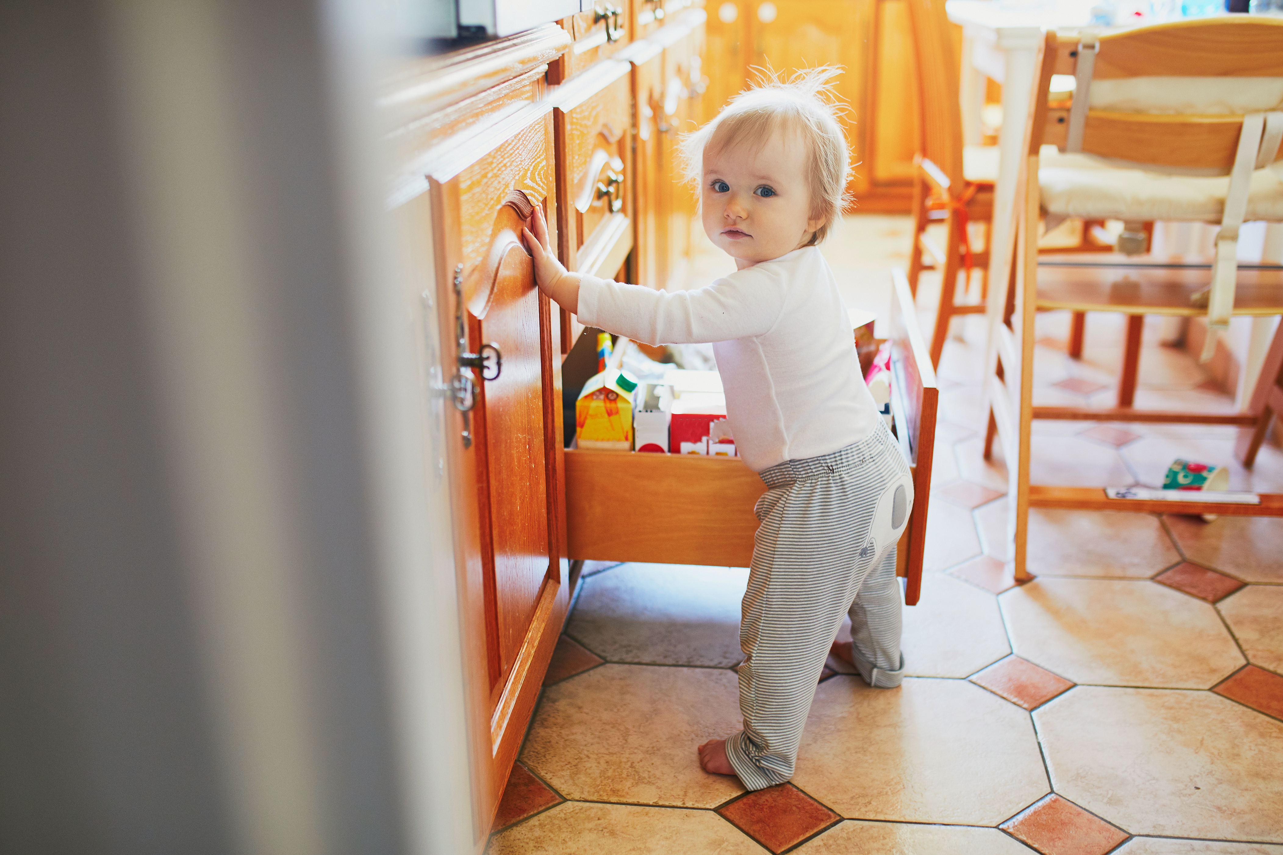 Toddler standing at an open drawer in the kitchen