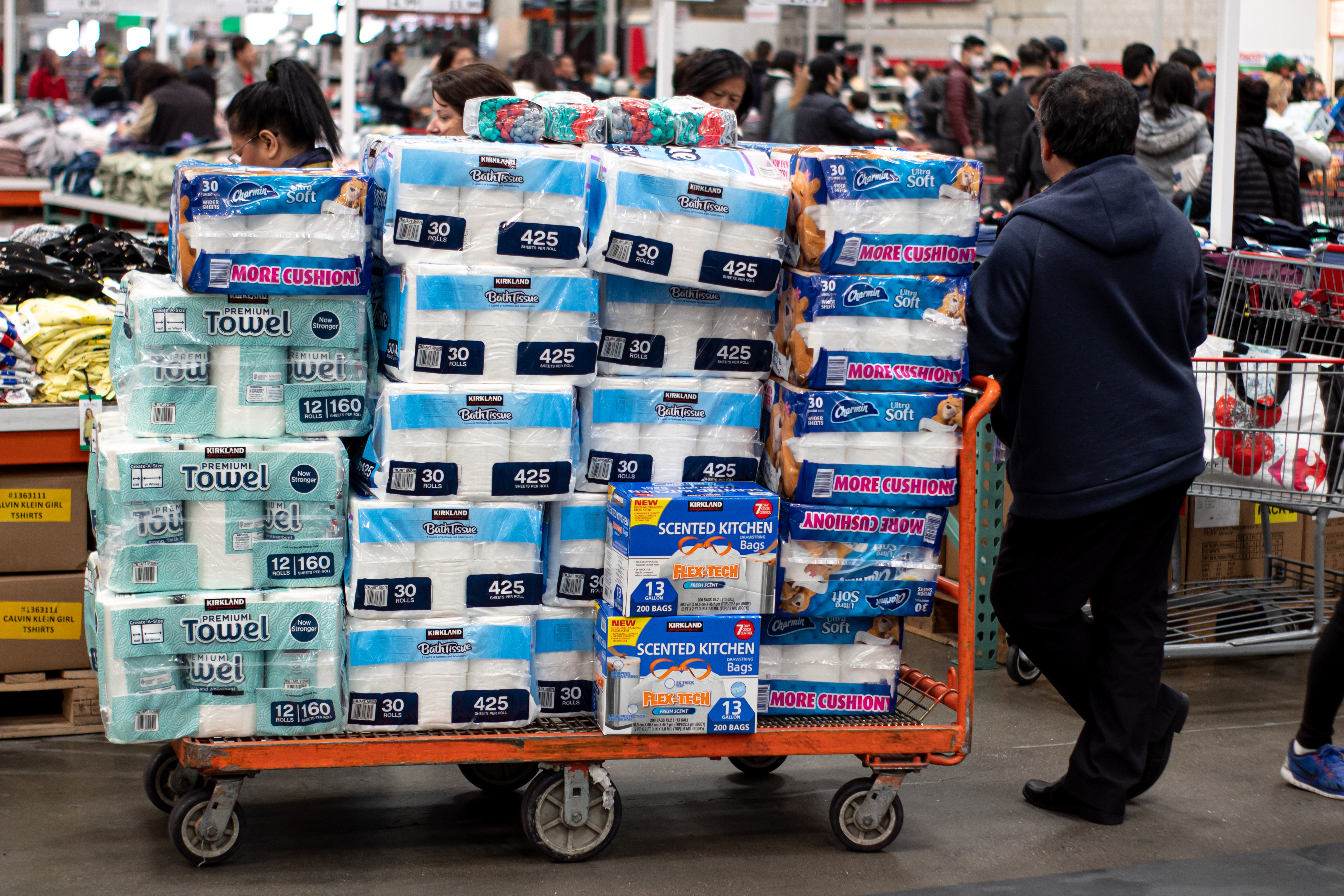 Man with a stack of toilet paper in his shopping cart