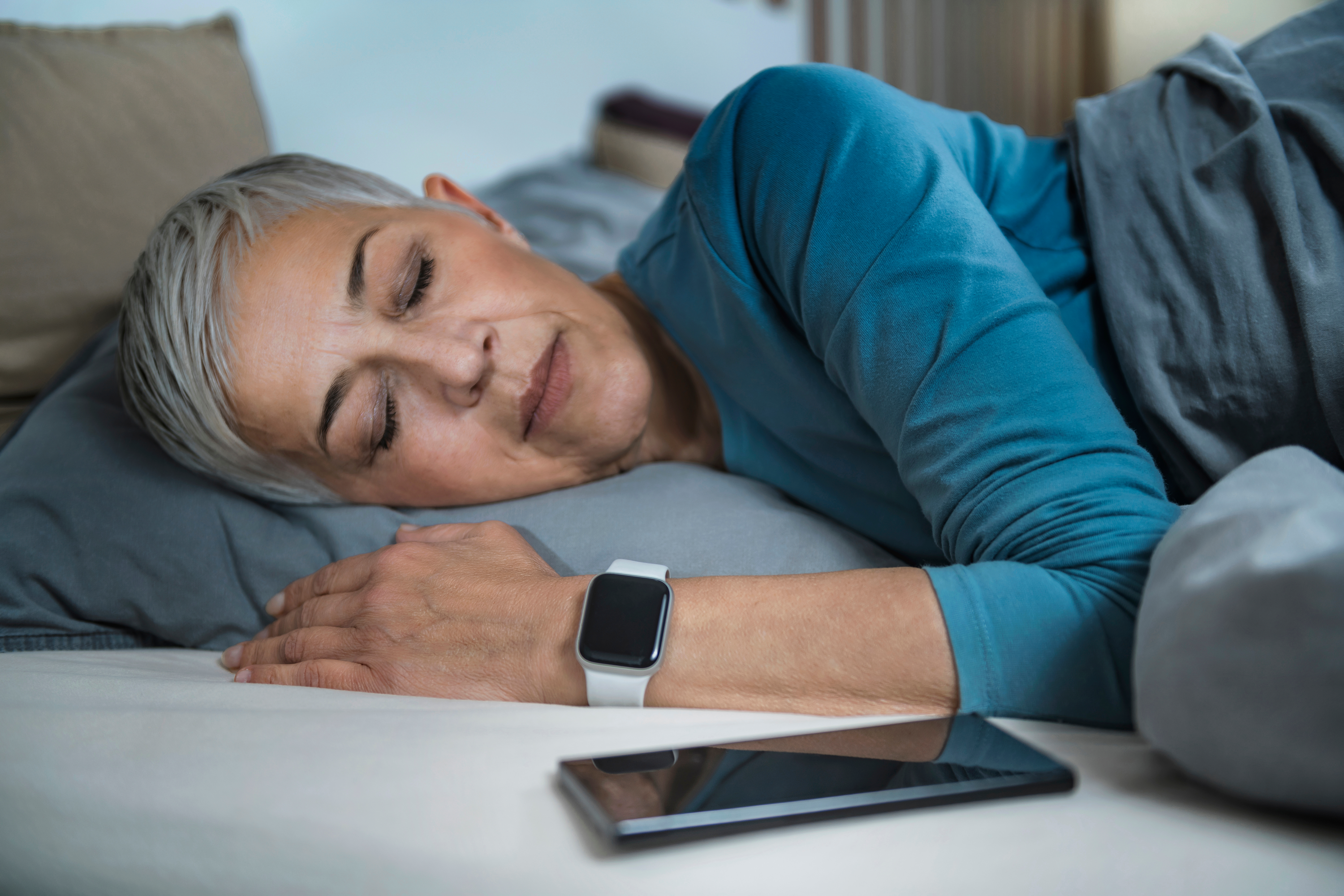 Sleeping woman wearing an Apple Watch with a phone next to her