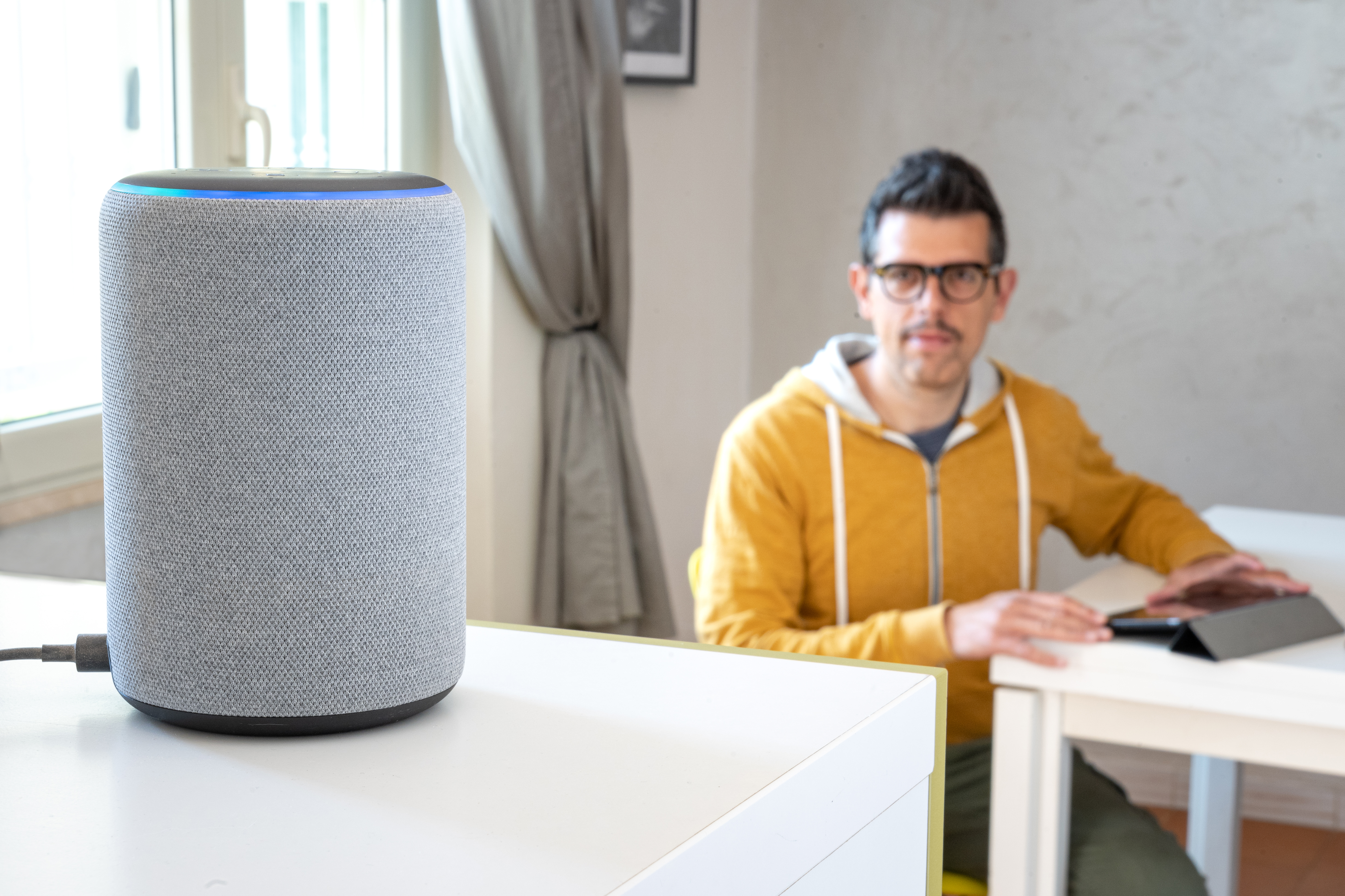 Man sitting at a table looking at an Amazon Alexa