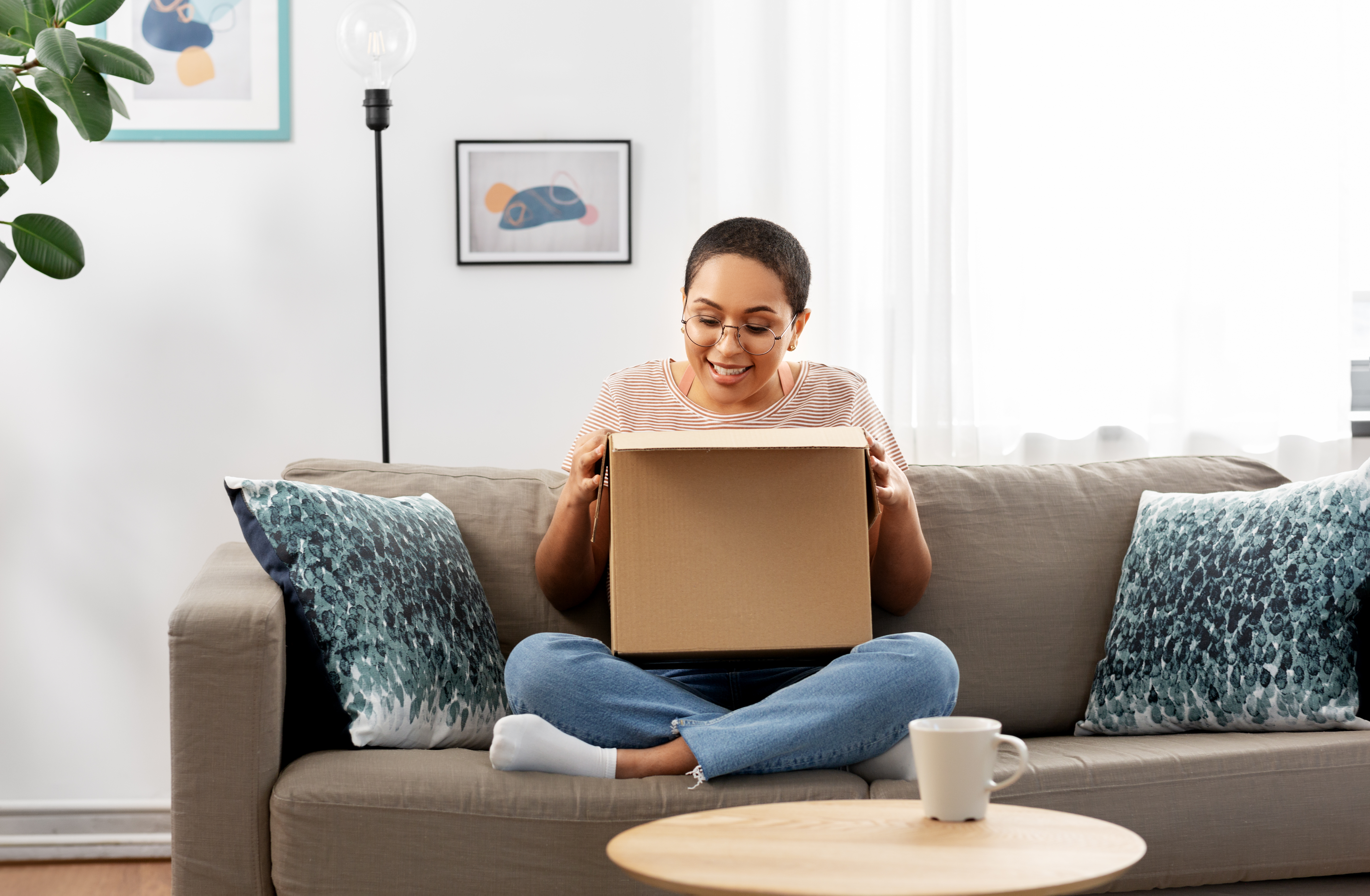 Woman sitting on the couch smiling looking into a box