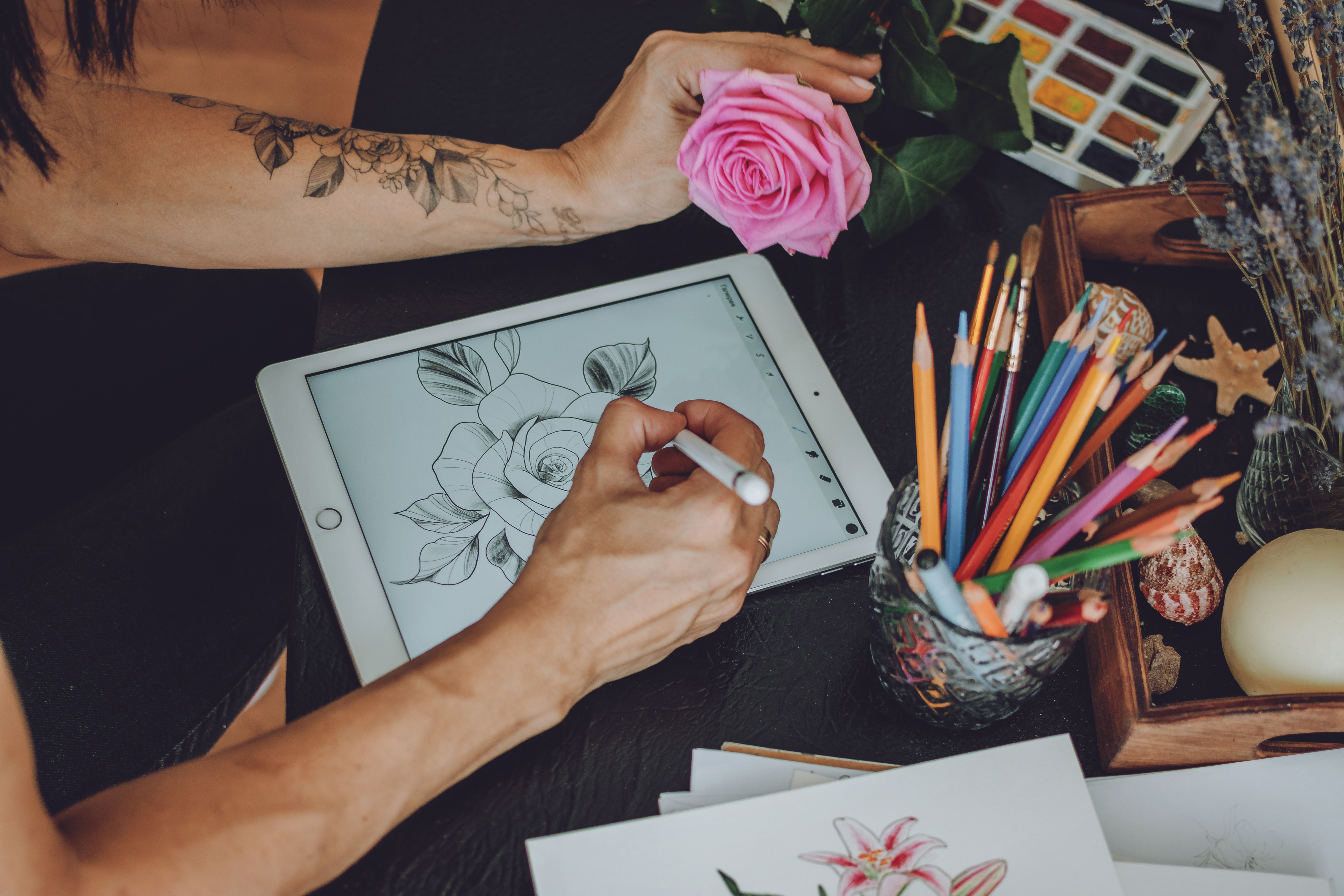 Person using an Apple Pencil to draw an image of a rose on an iPad