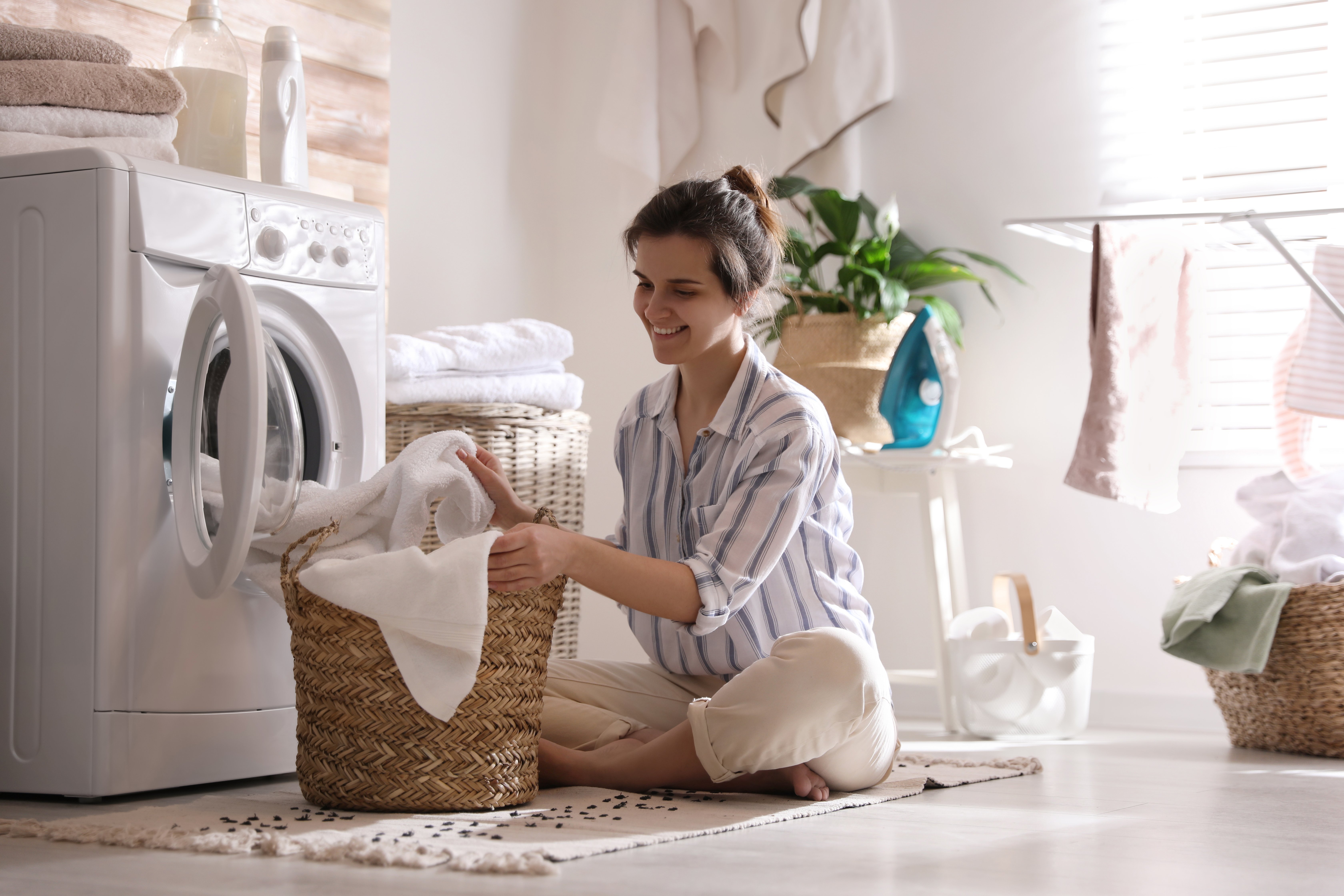 Woman wearing a striped shirt sitting on the ground doing laundry