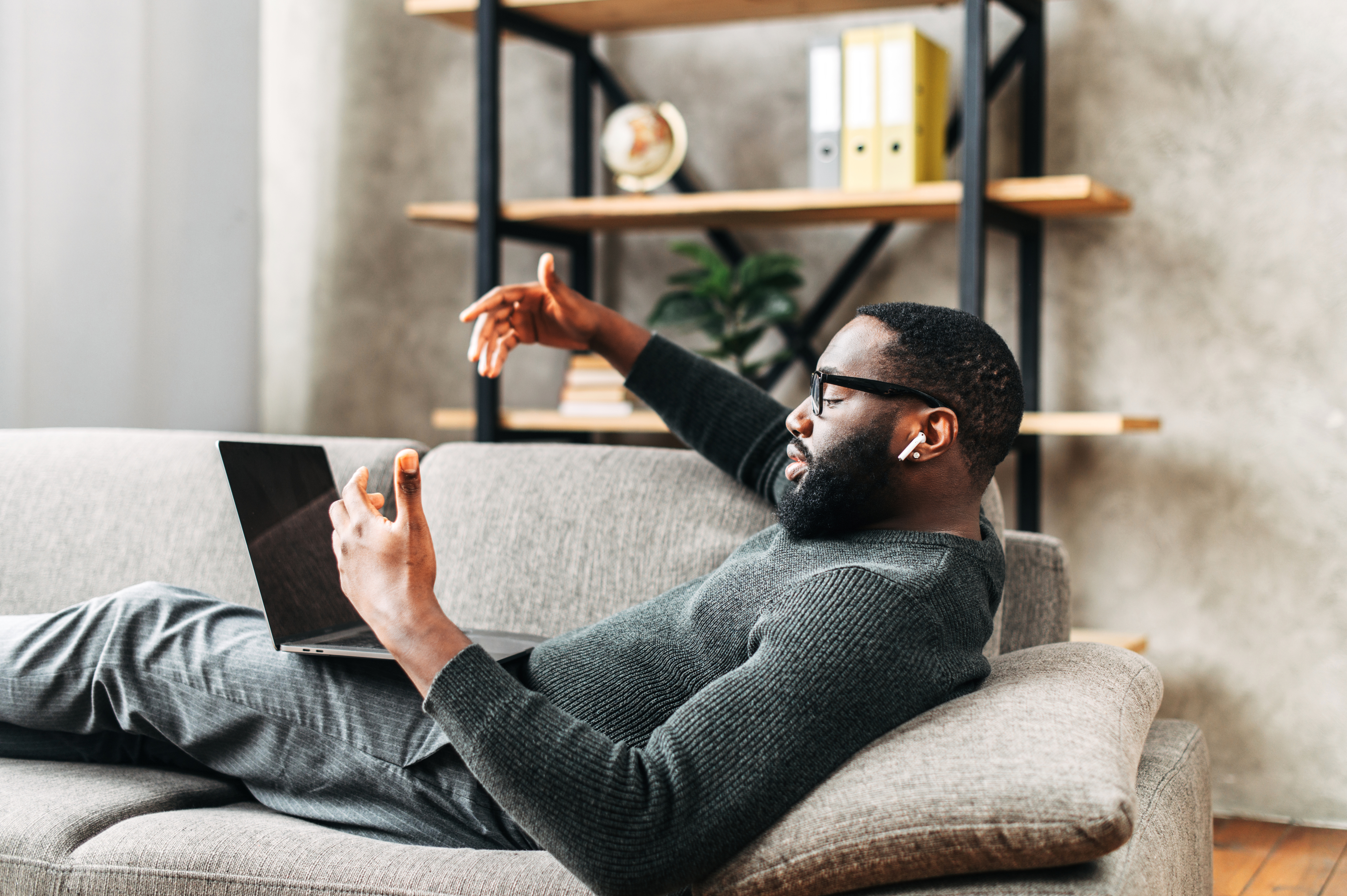 Man lying on the couch on his laptop with AirPods in