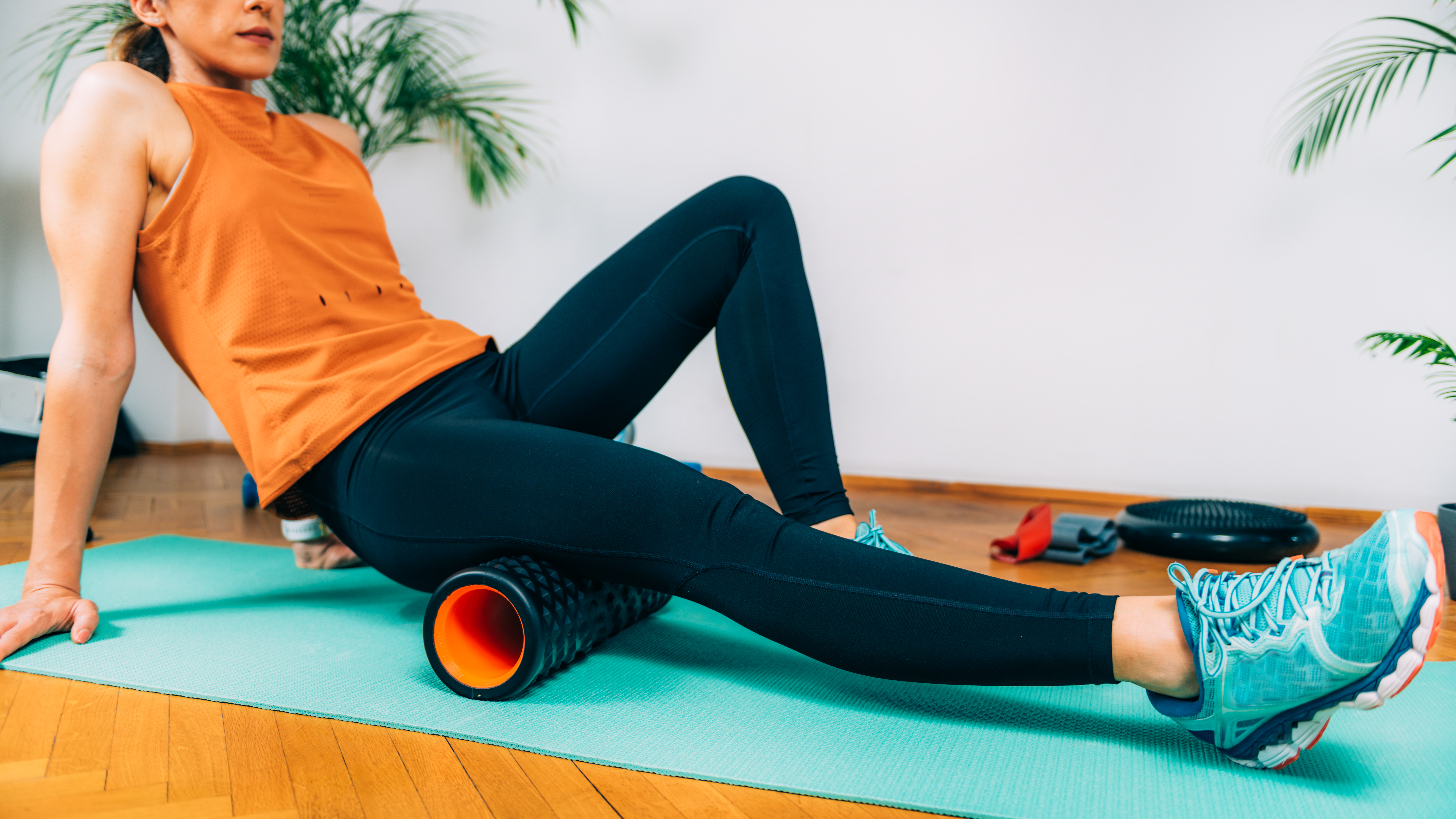 Woman using a foam roller on a yoga mat