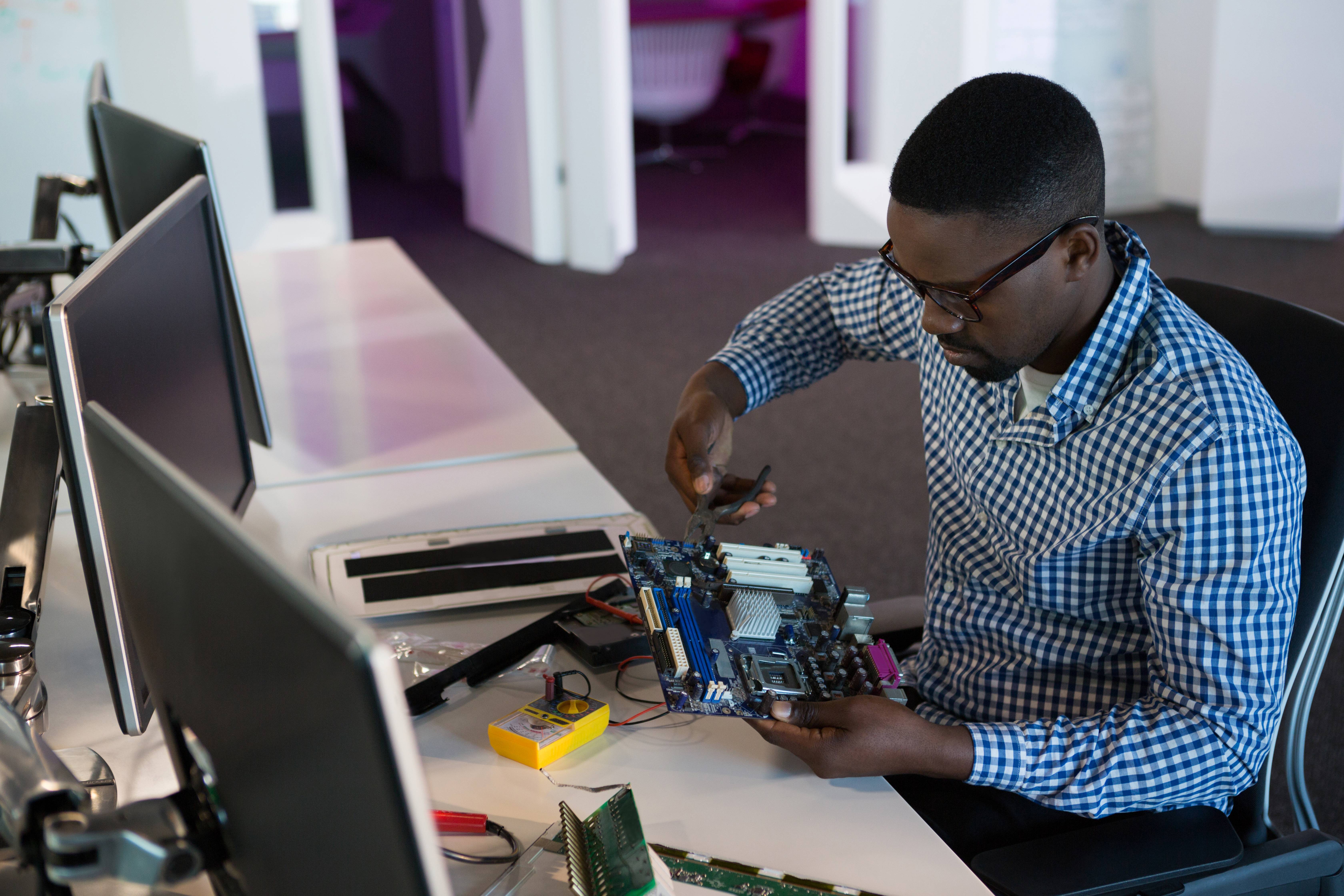 Man sitting at a desk using tools to fix a computer