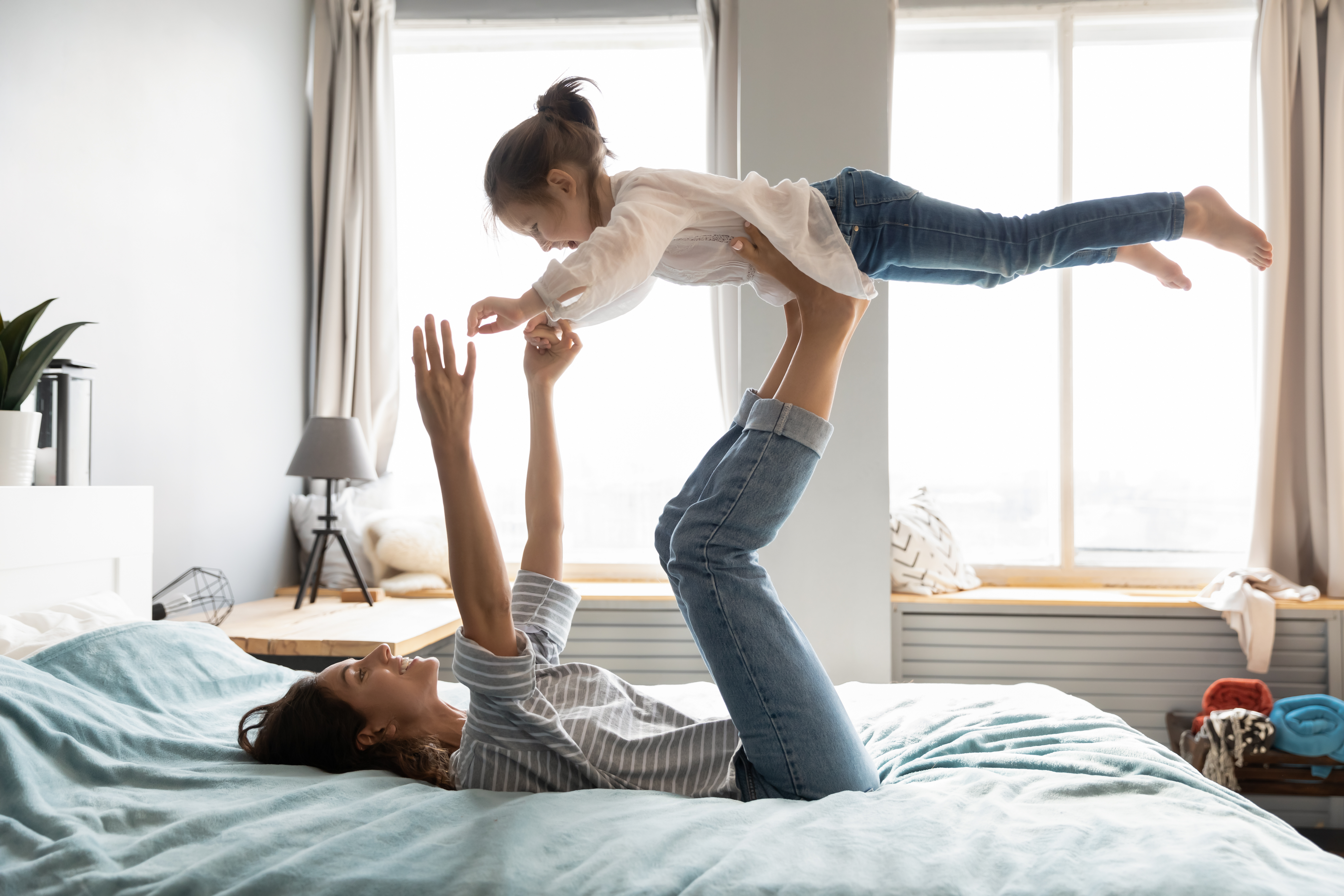 Woman and her daughter playing on the bed