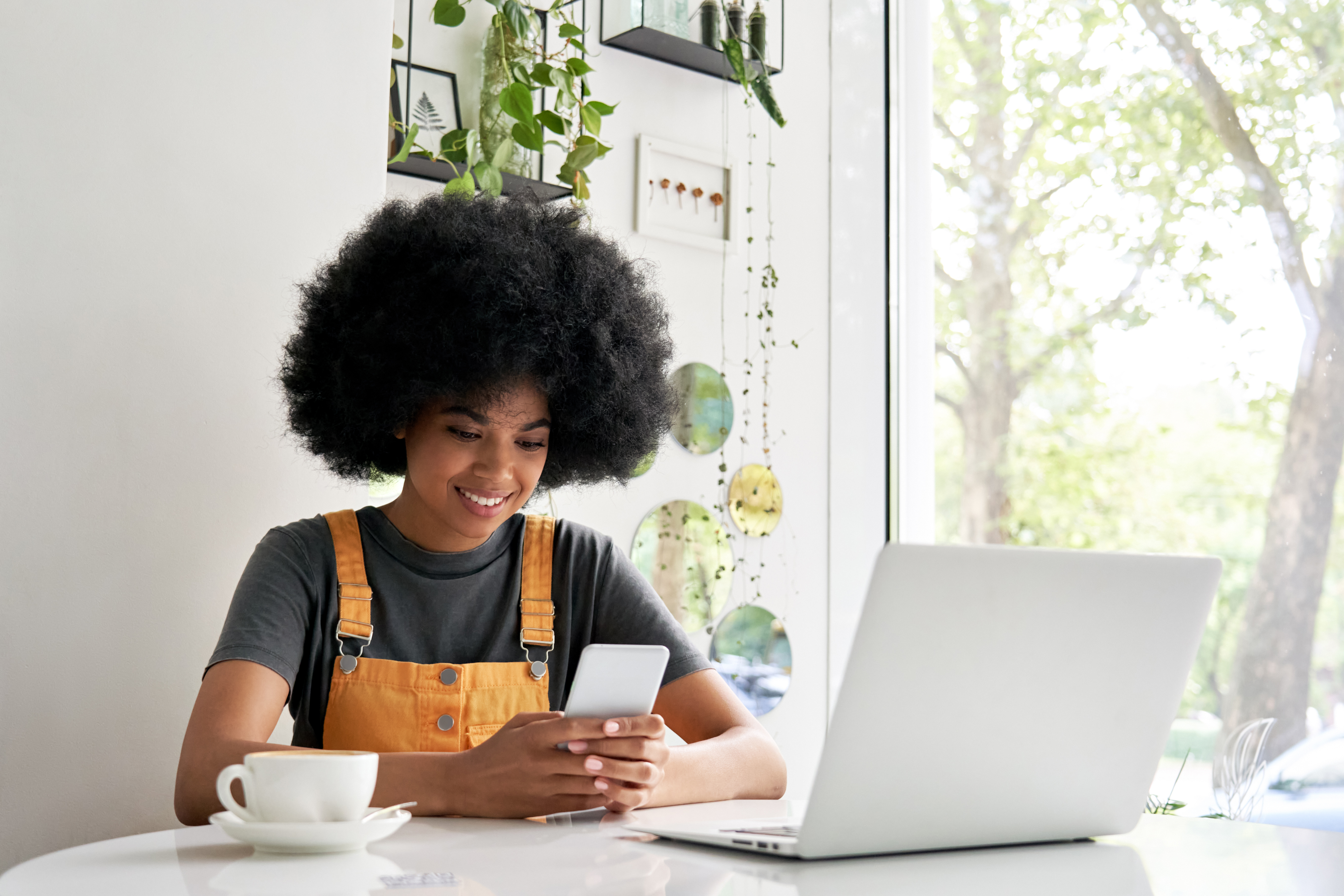 Woman sitting in a coffee shop smiling looking at her phone