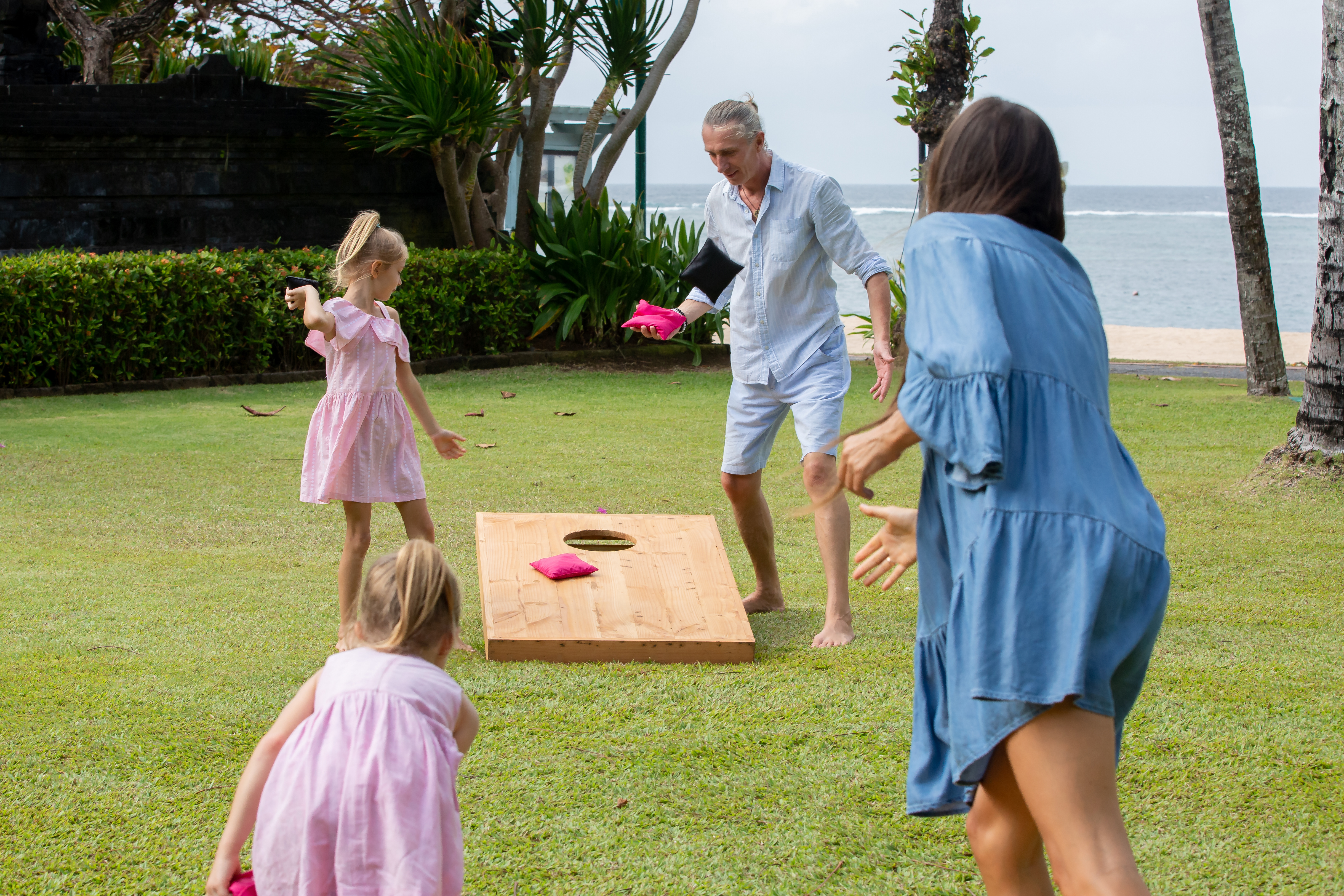 Family playing Cornhole together outside