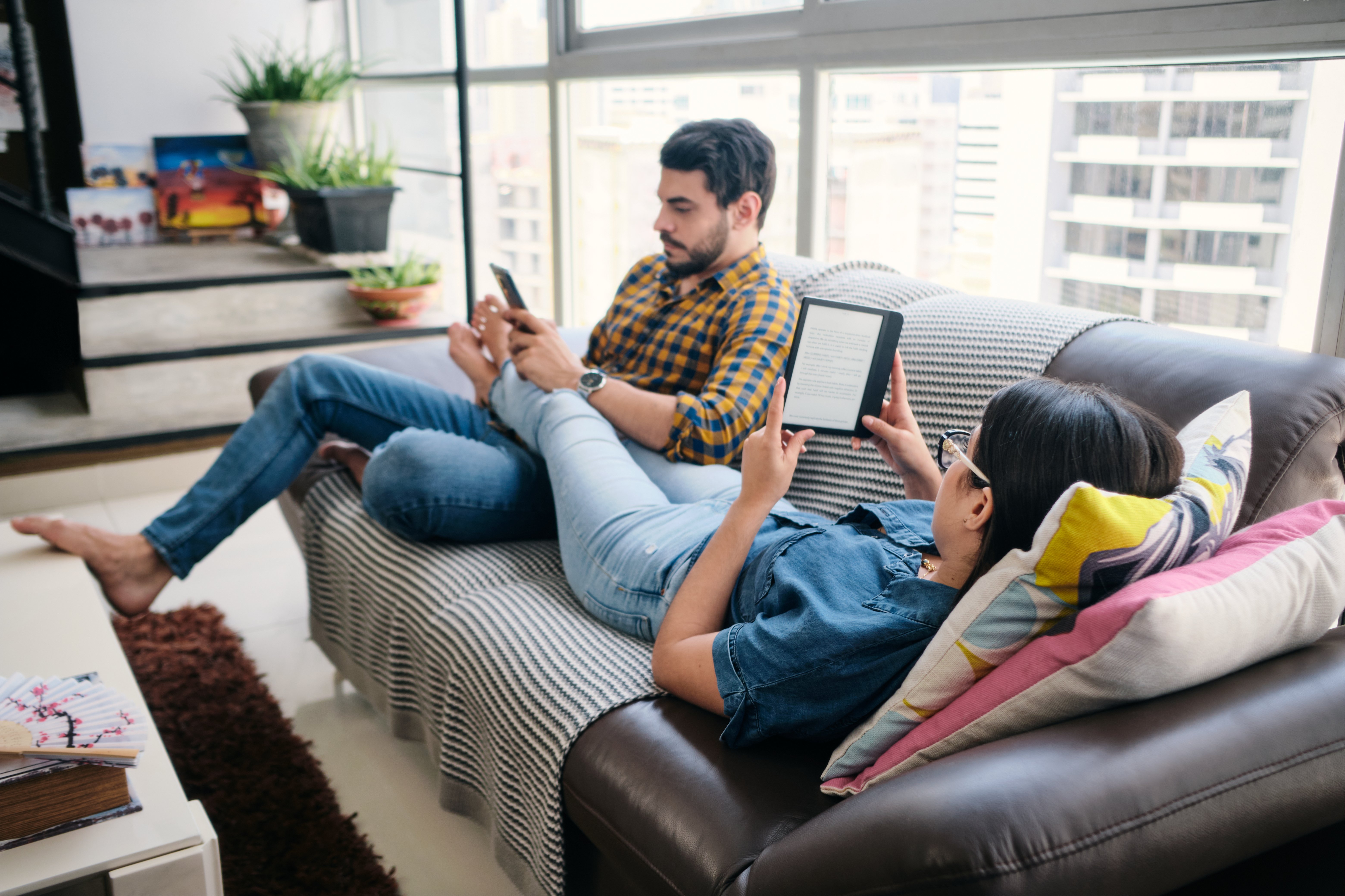 Man and woman sitting on couch using eReaders