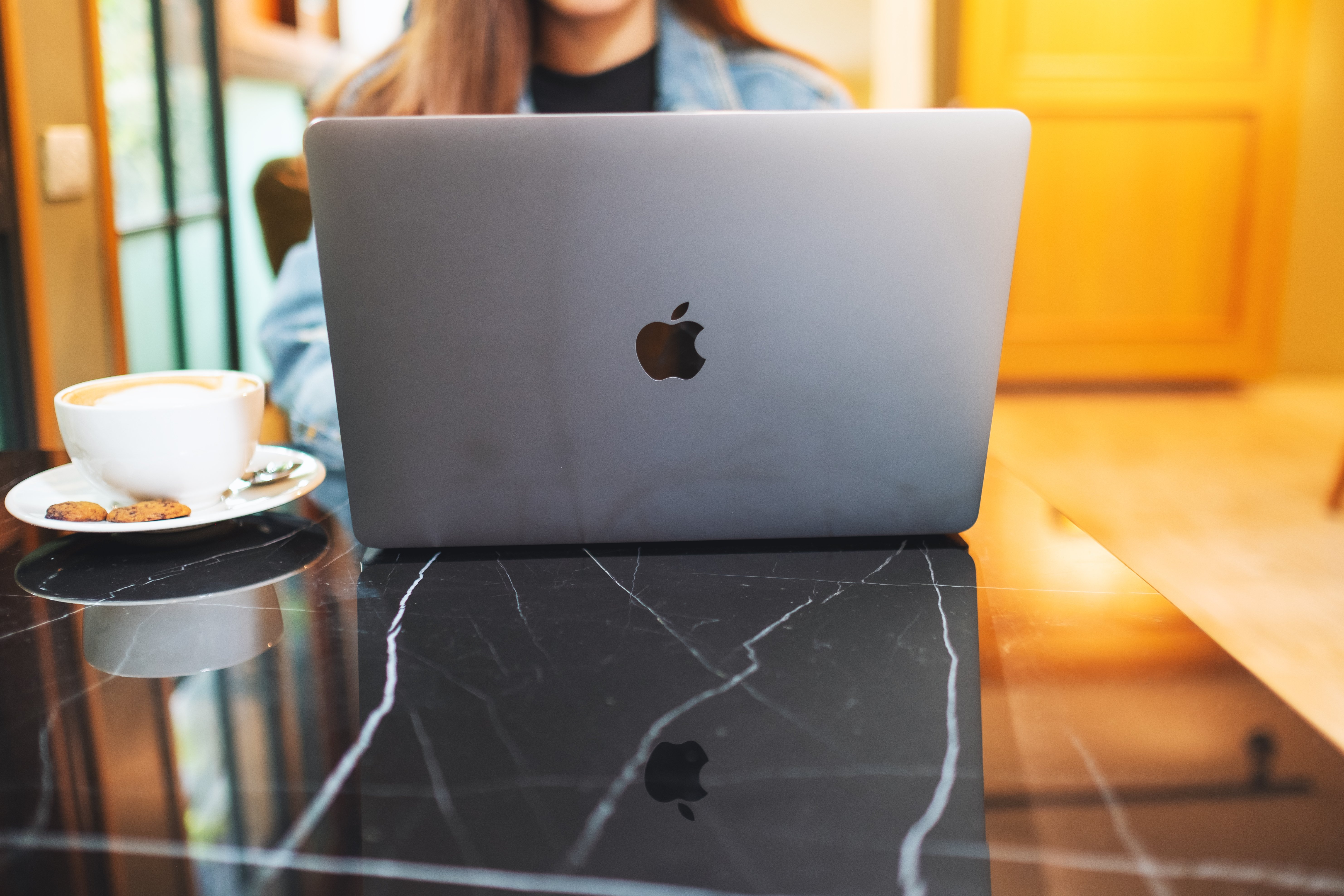 Woman sitting at a coffee shop using a MacBook Pro