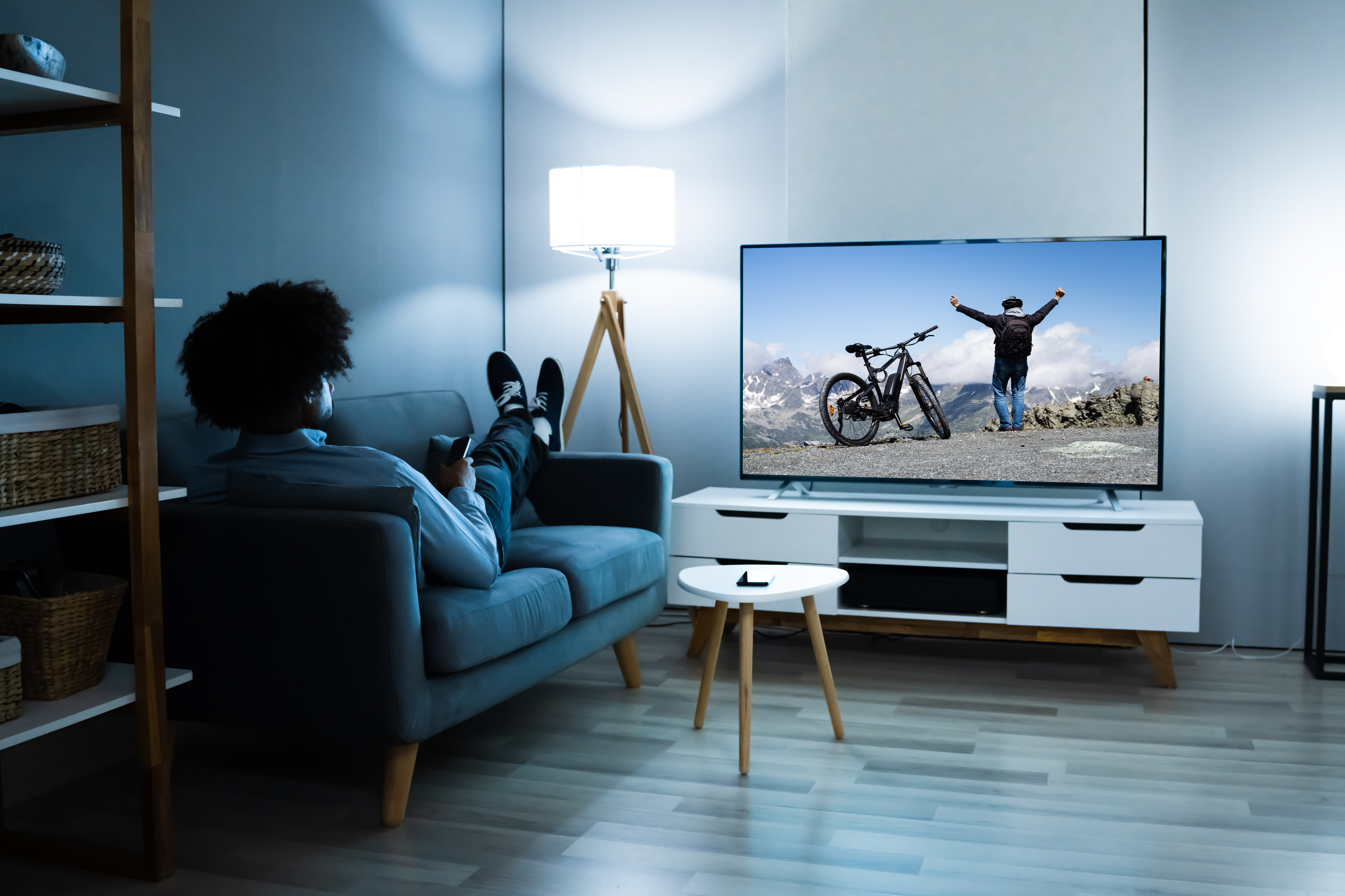 Man lying on a blue couch watching TV