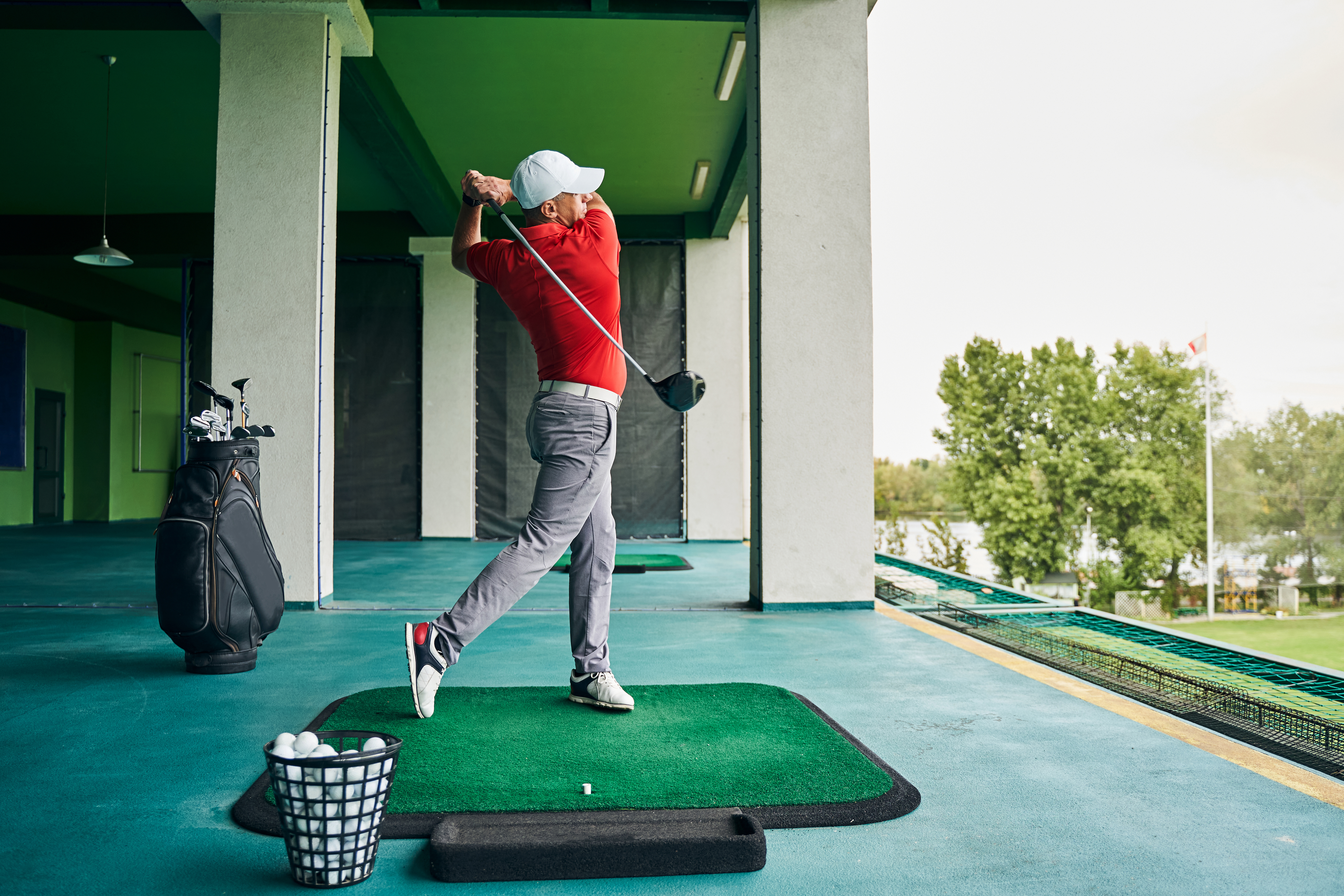 Man wearing a red shirt swinging a golf club