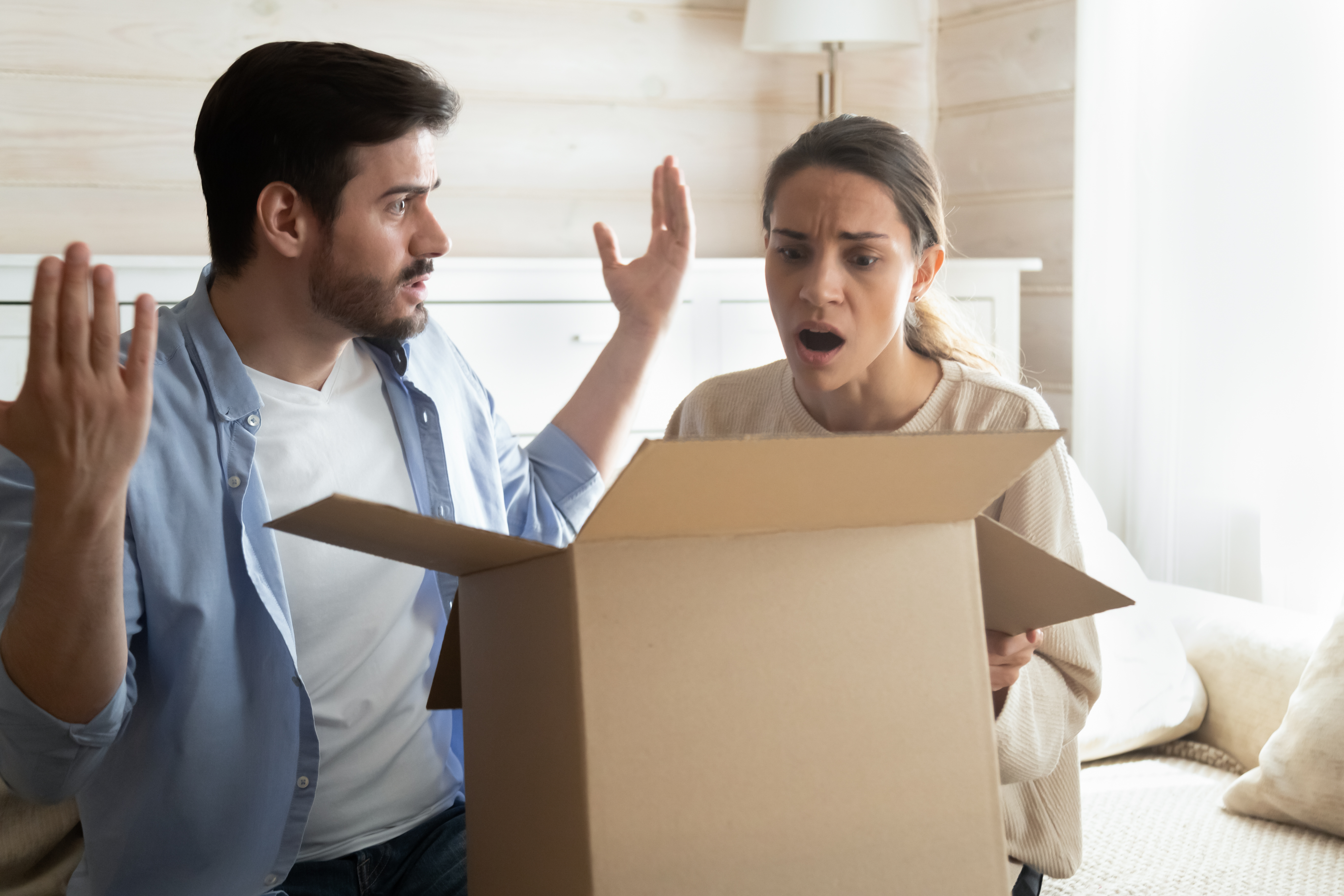 Man and woman in disbelief looking at a cardboard box