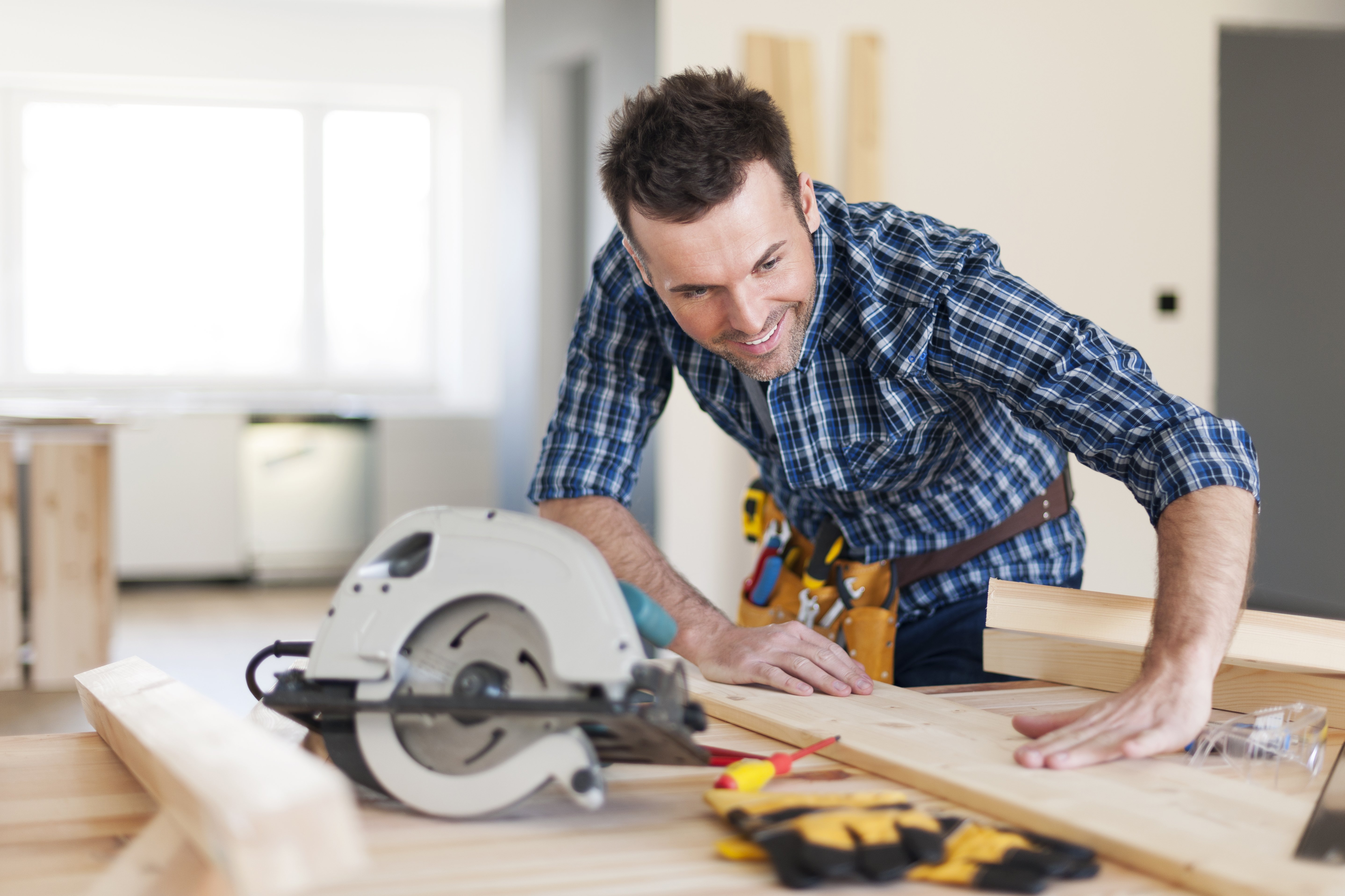 Man measuring wood to cut with a saw