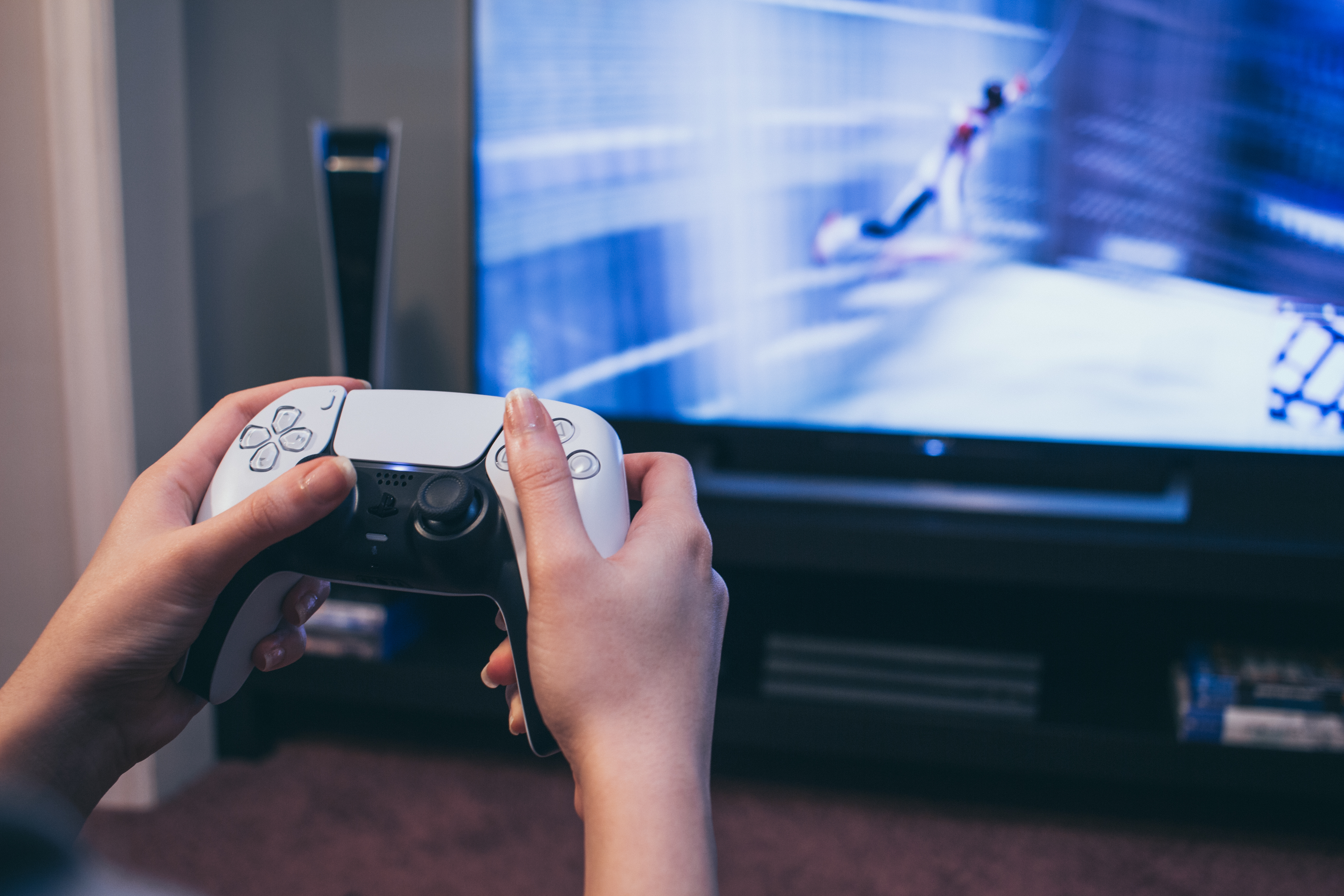 Person holding a PlayStation 5 controller while playing a video game