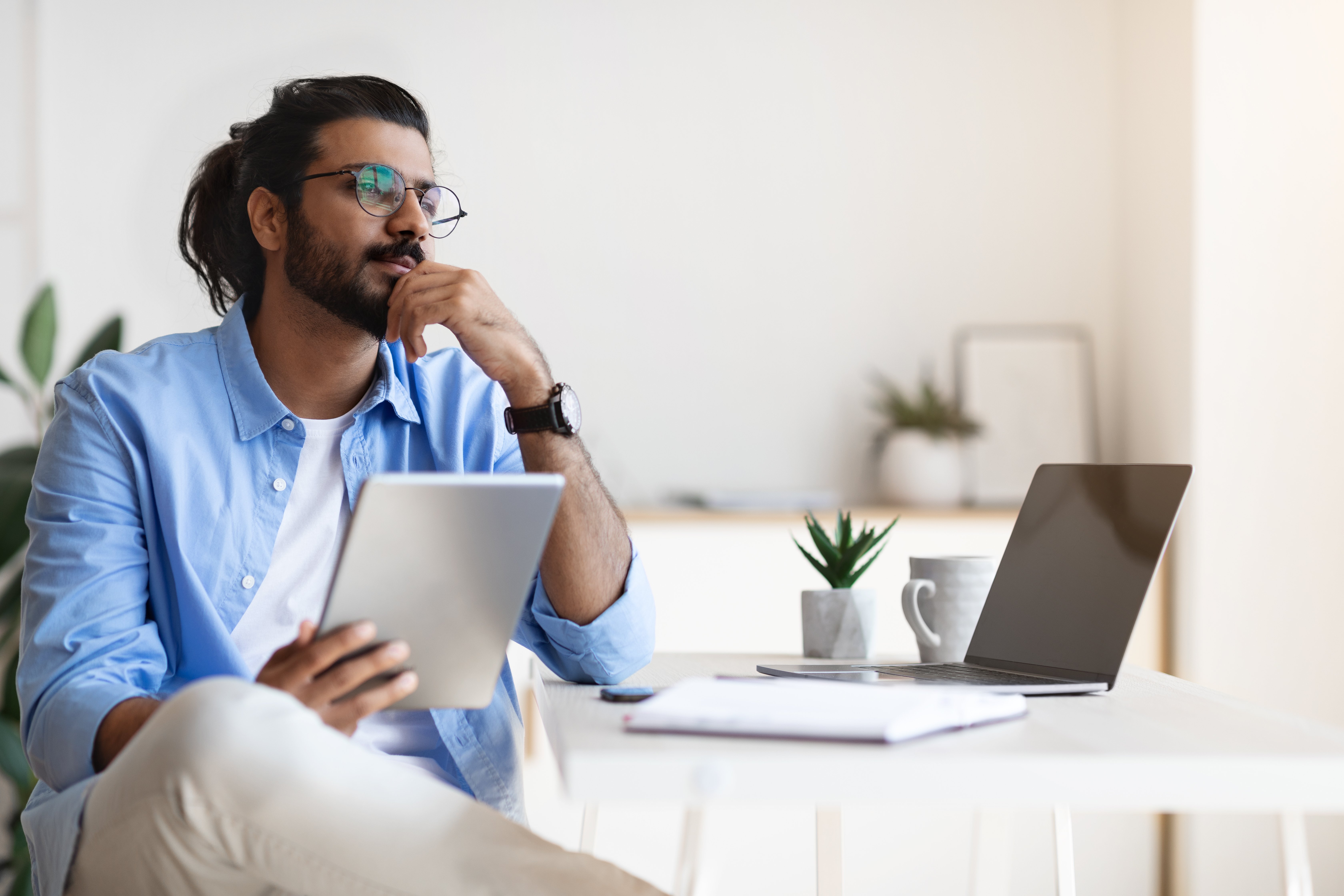 Man sitting at a desk holding a tablet