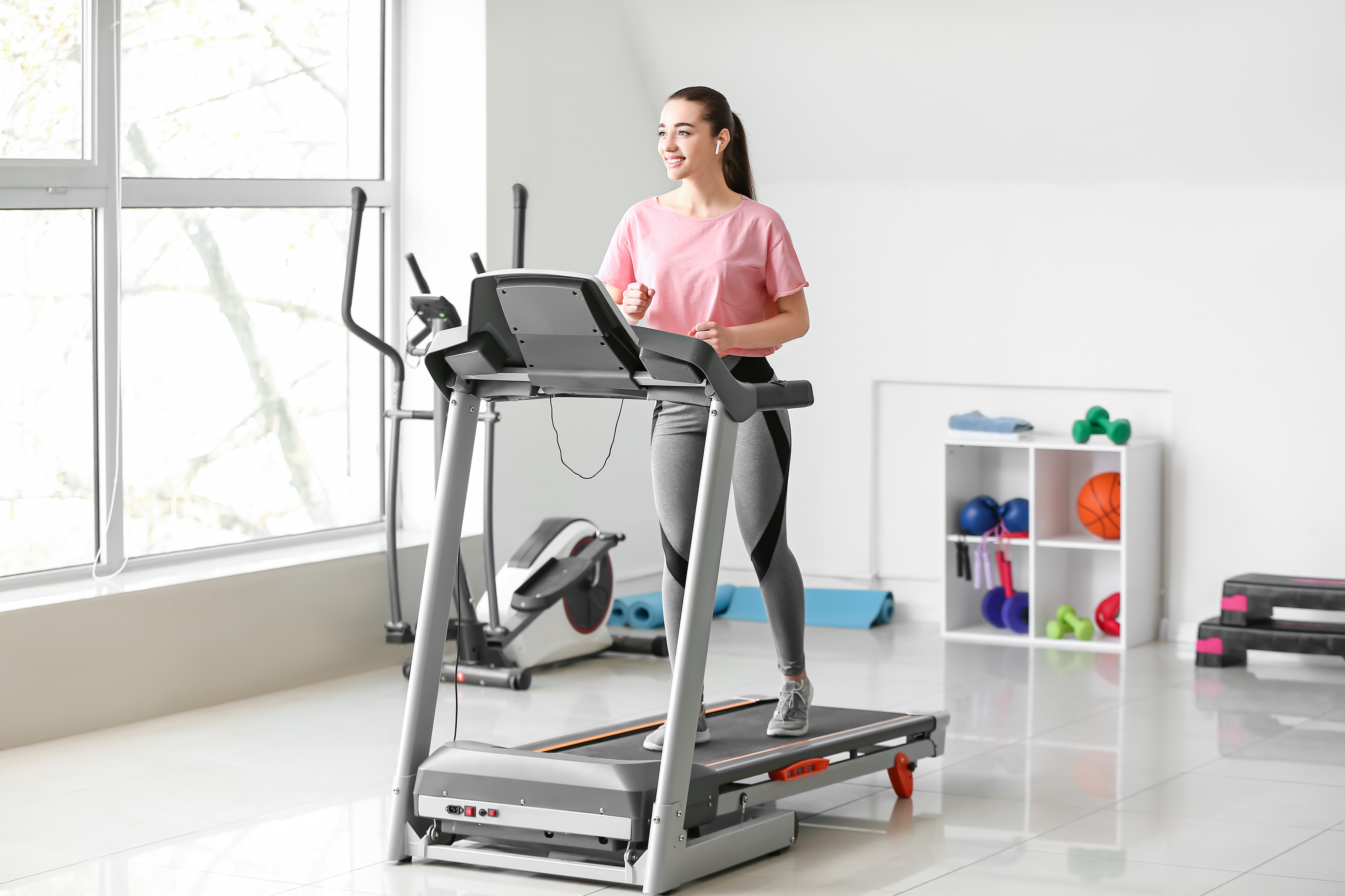 Woman wearing pink shirt walking on treadmill