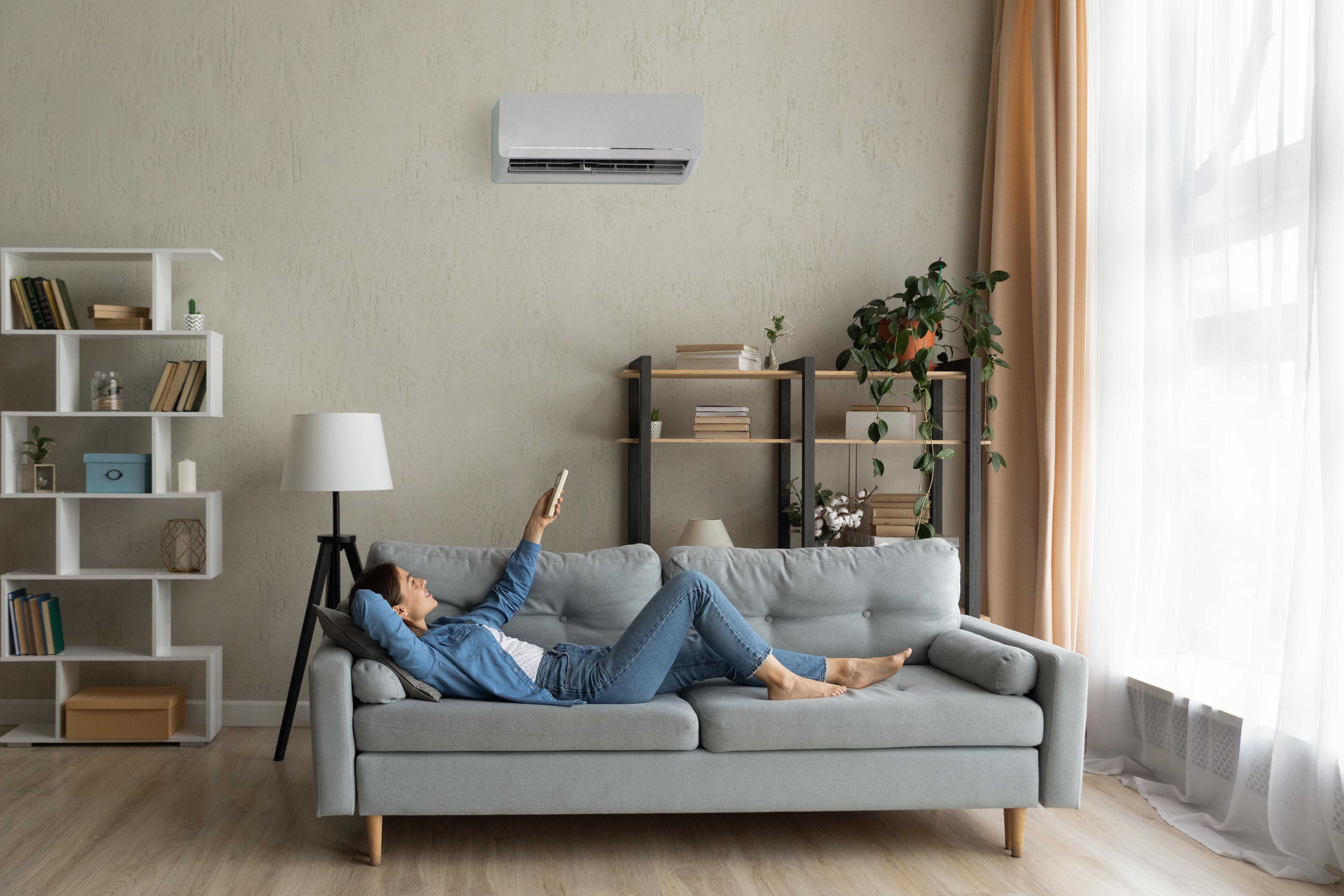 Woman relaxing on couch and adjusting air conditioner