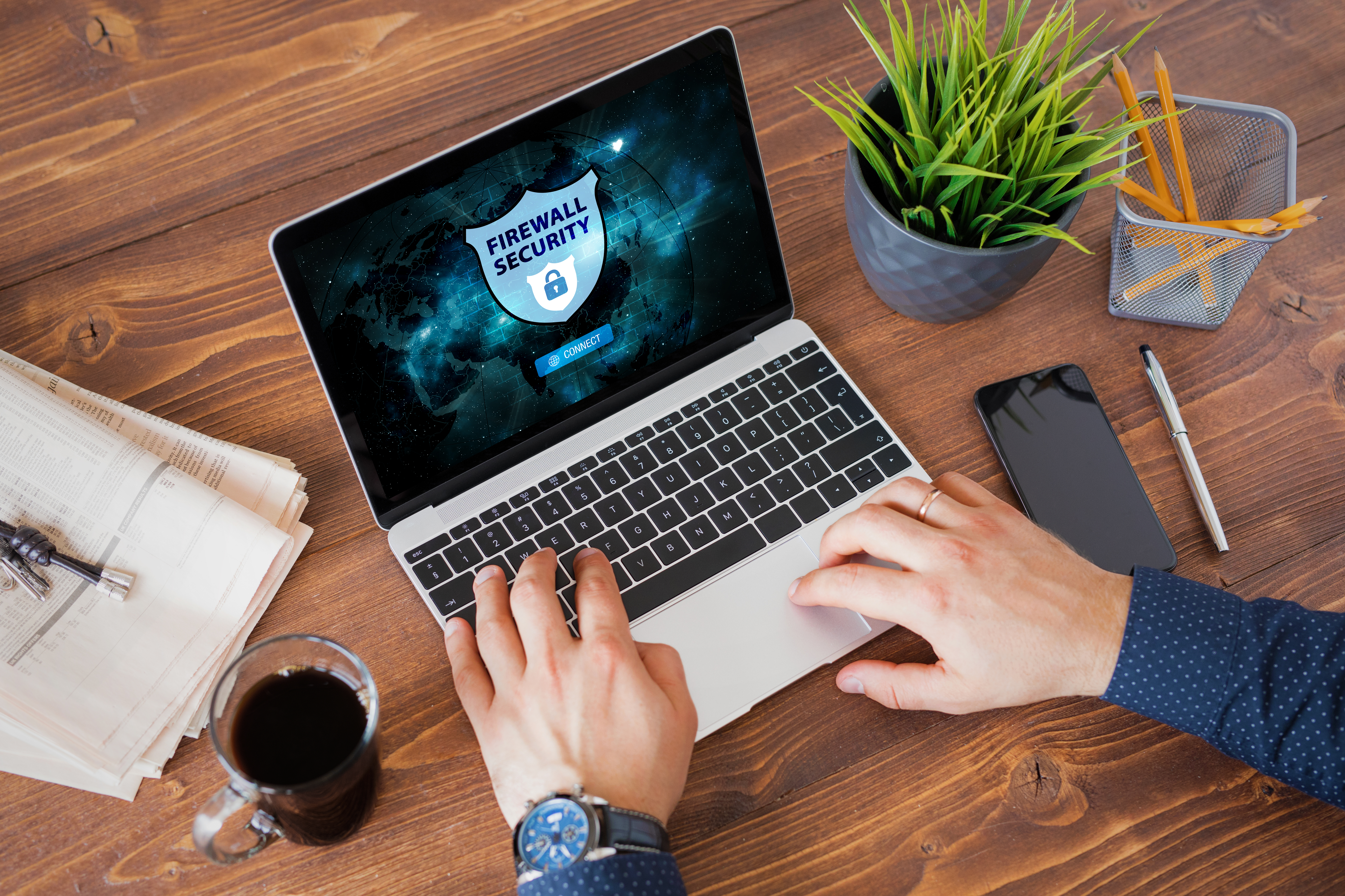 Man on a Macbook with an icon for firewall security on the screen