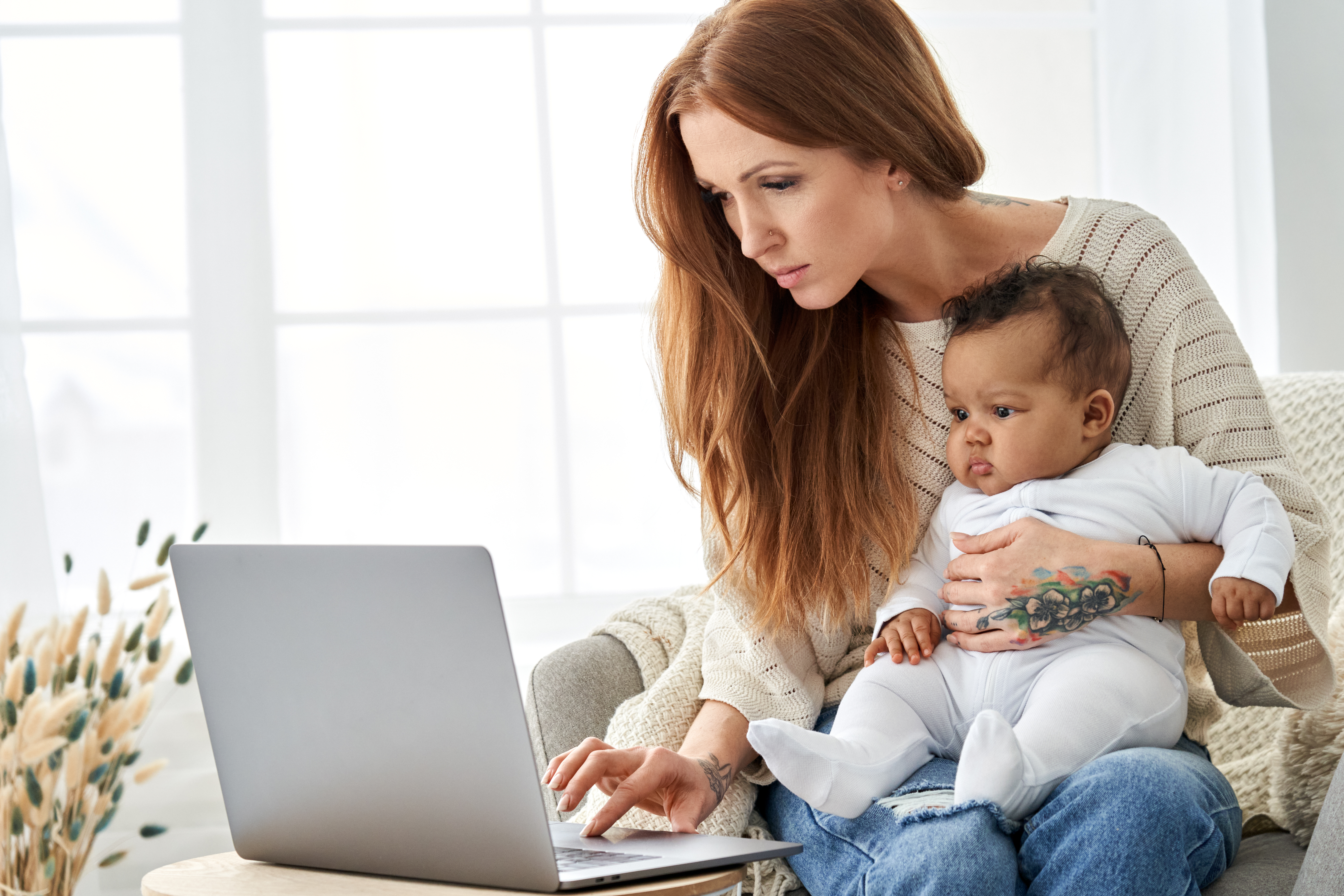 Mom holding her baby on her lap looking at a laptop